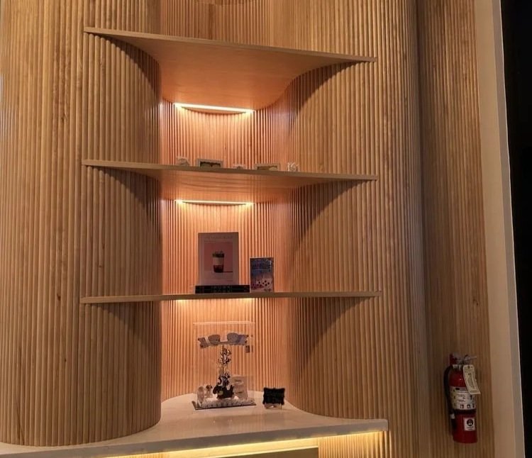 Wooden display shelf with built-in lighting at Social Tea Capitol Hill, Seattle WA, displaying small decorative items, with a fire extinguisher on the right side.