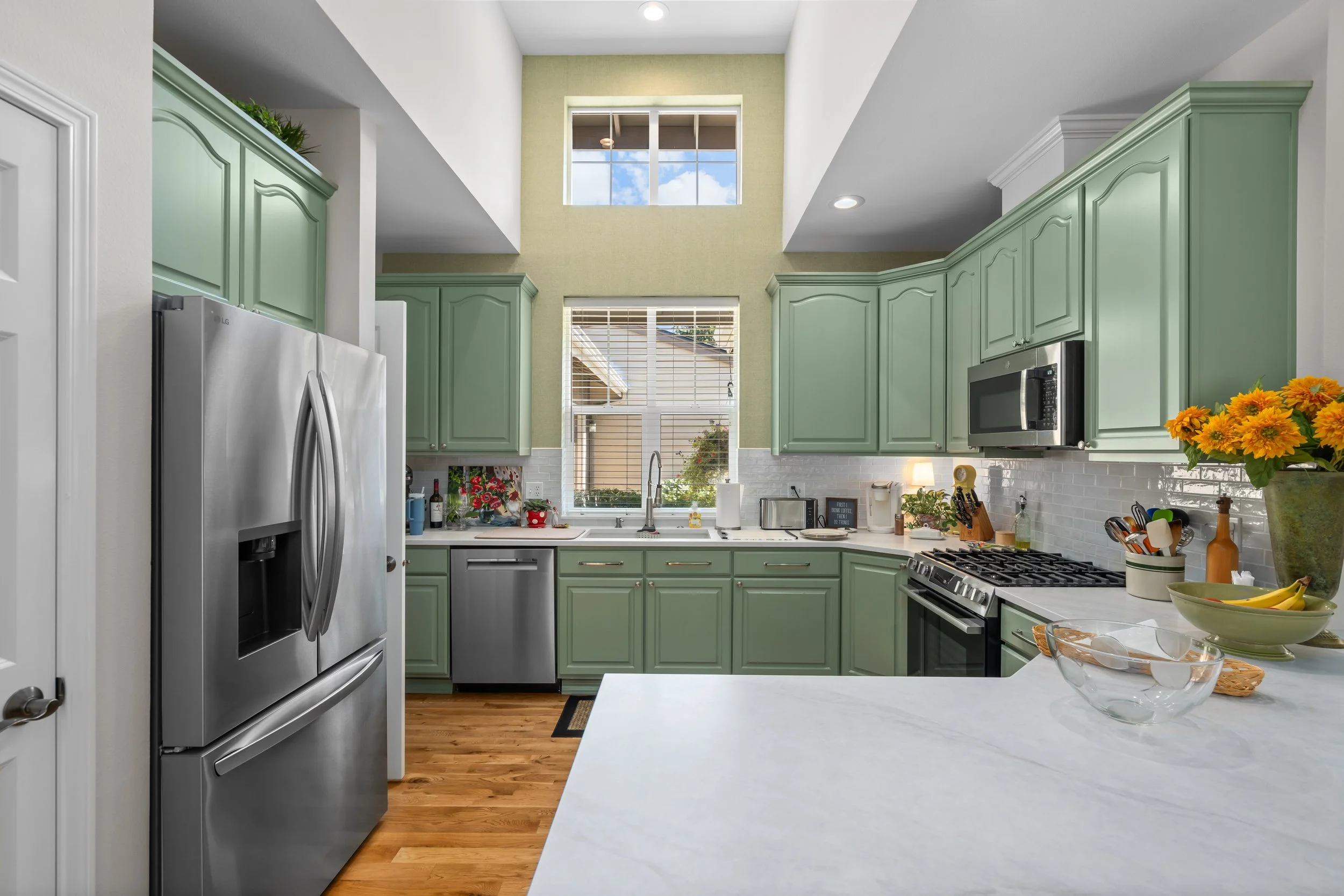 The Mollie House Transformation — remodeled kitchen with stainless steel refrigerator, quartz island and green cabinets, Redmond interior remodel