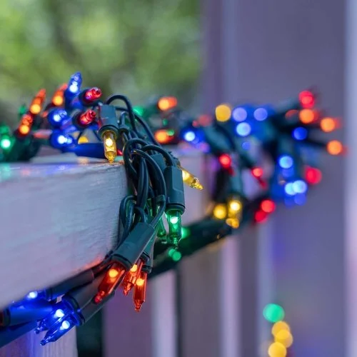Colorful Christmas string lights wrapped around a railing with blurred background