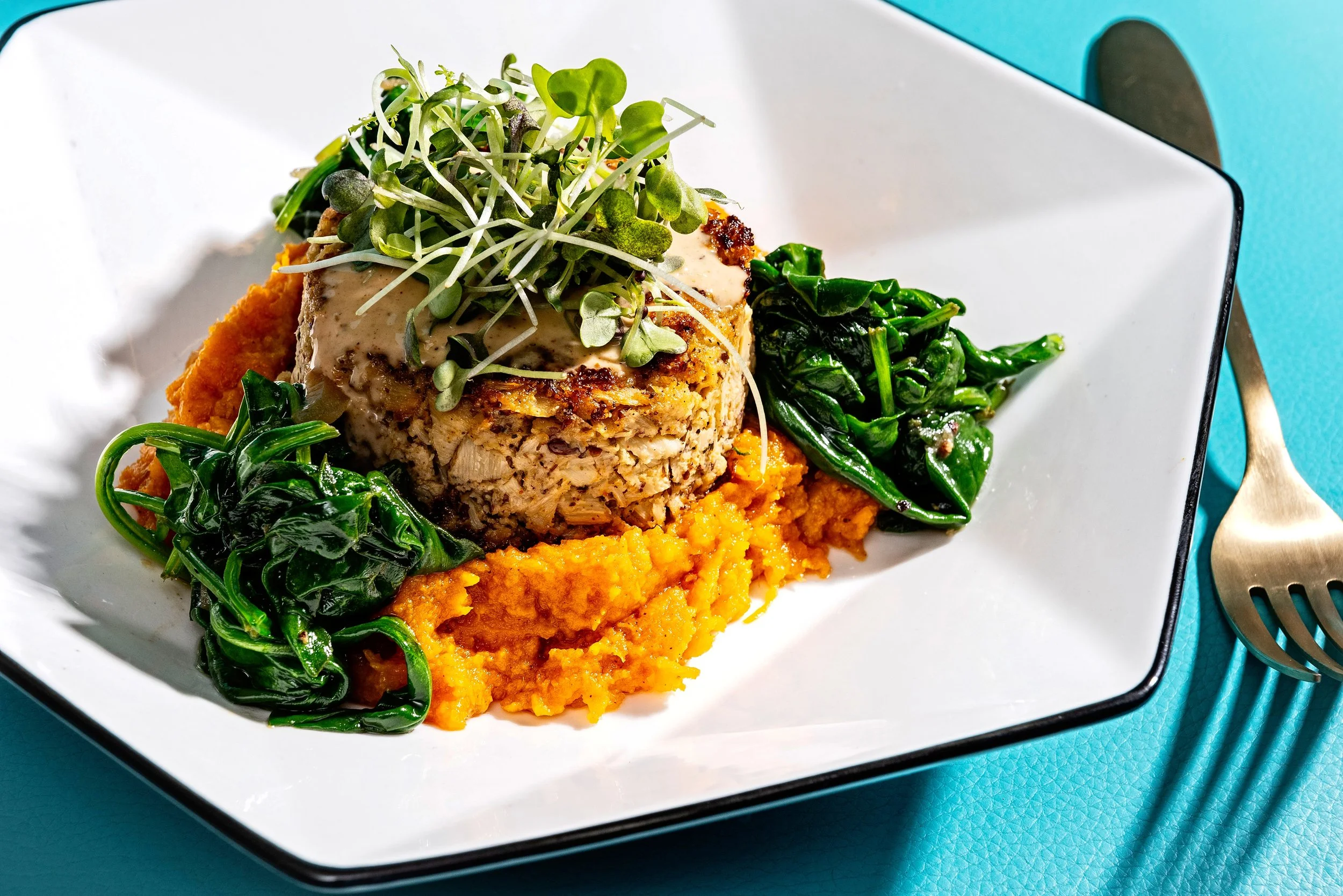 Luxury plant-based crab cake with sweet potato purée, sautéed greens, and microgreens by Gingerbēet Botanical Cuisine in Washington, DC.