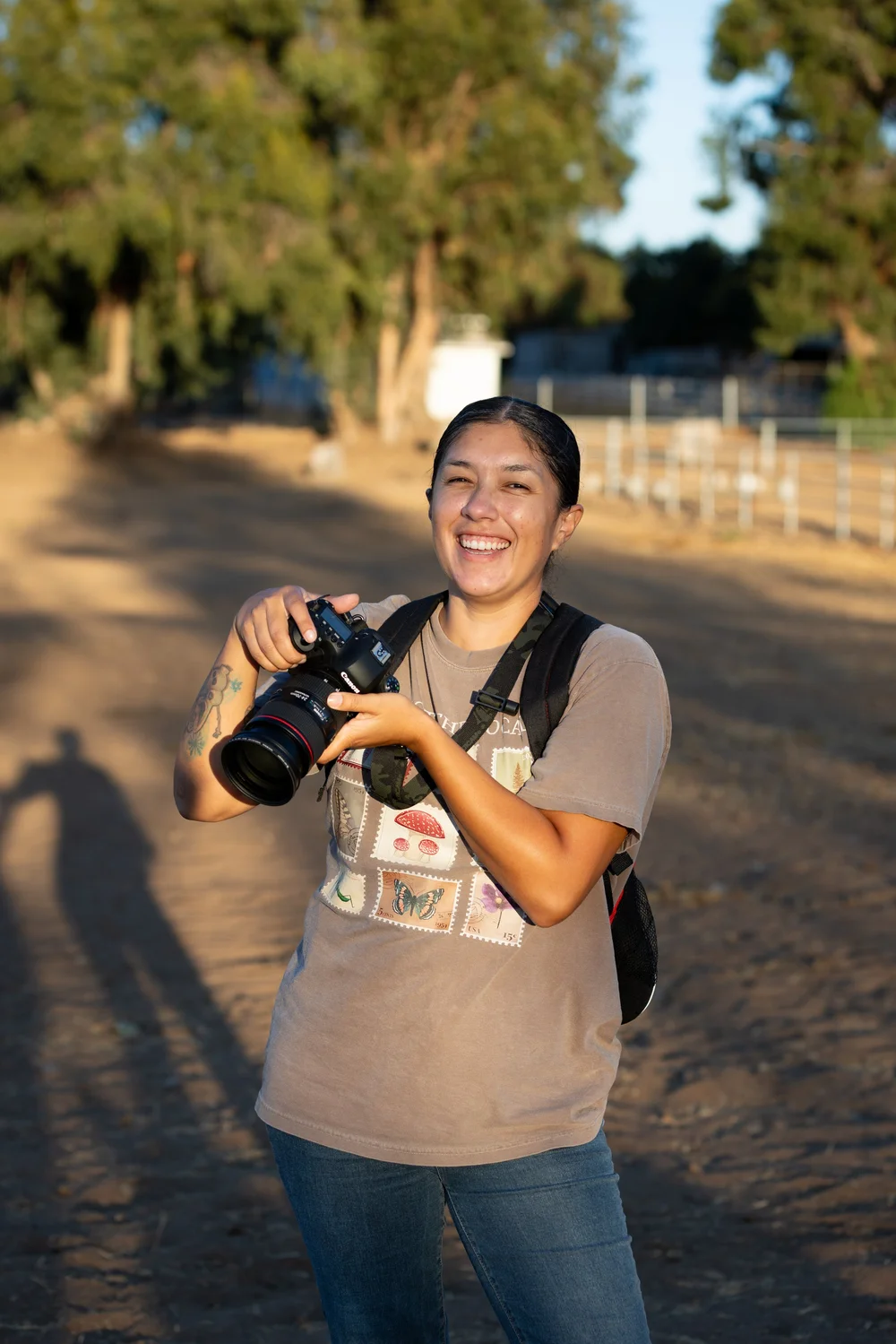 Debra, the photographer behind Hue & Hide, smiling and holding her camera