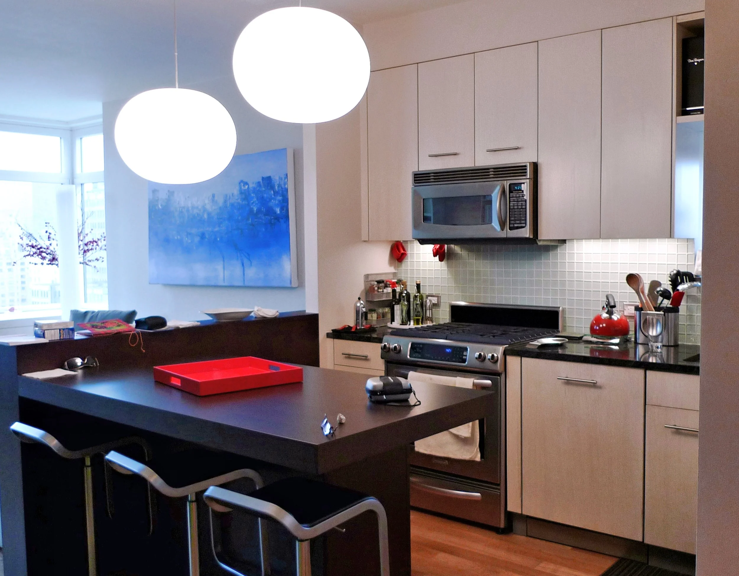 Cucina moderna nei toni del beige con mobili dipinti, piano di lavoro nero e penisola centrale.