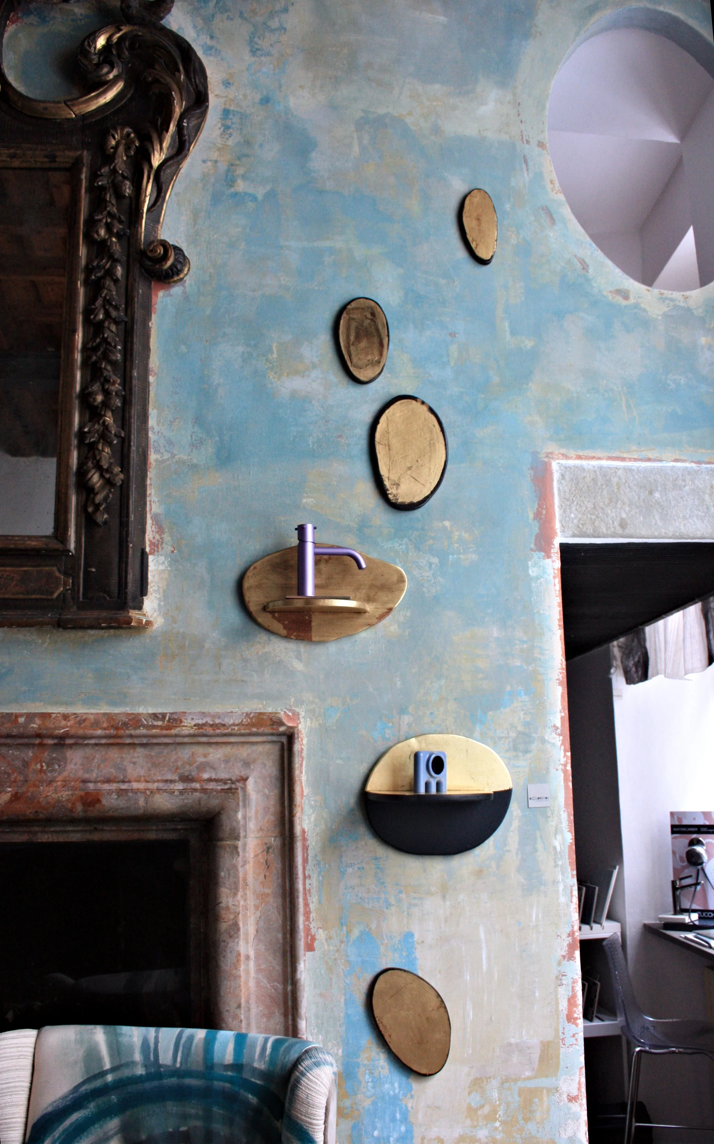 Parete delabré blu con mensole in legno dalle forme irregolari e composizione decorativa.
