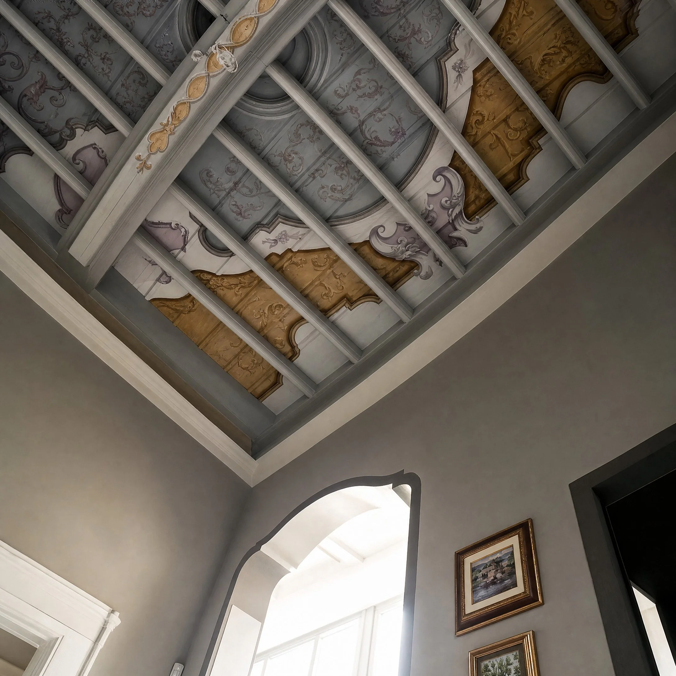 Scala e ingresso con ringhiera decorata, soffitto dipinto e decorazioni pittoriche sulle superfici.