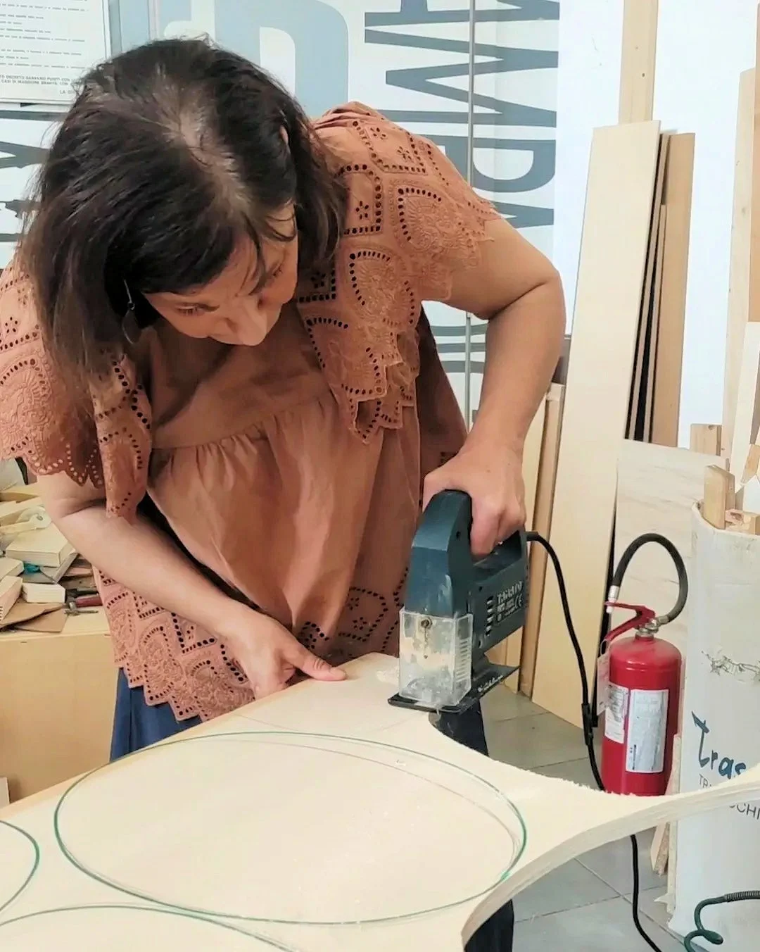 Una donna che lavora il legno con un seghetto alternativo in laboratorio.