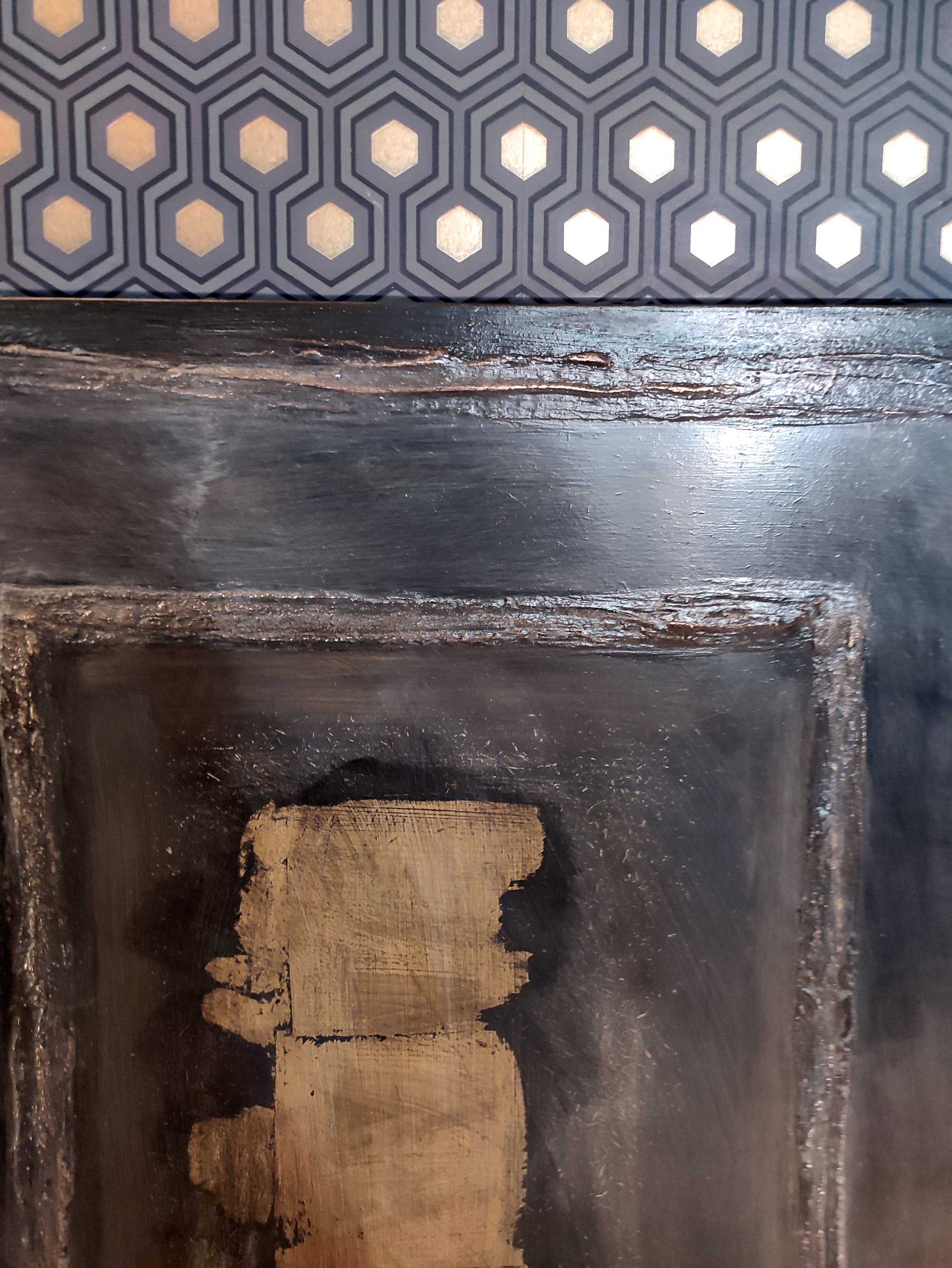 Dettaglio di una boiserie in legno con finitura vissuta e elemento decorativo in metallo.