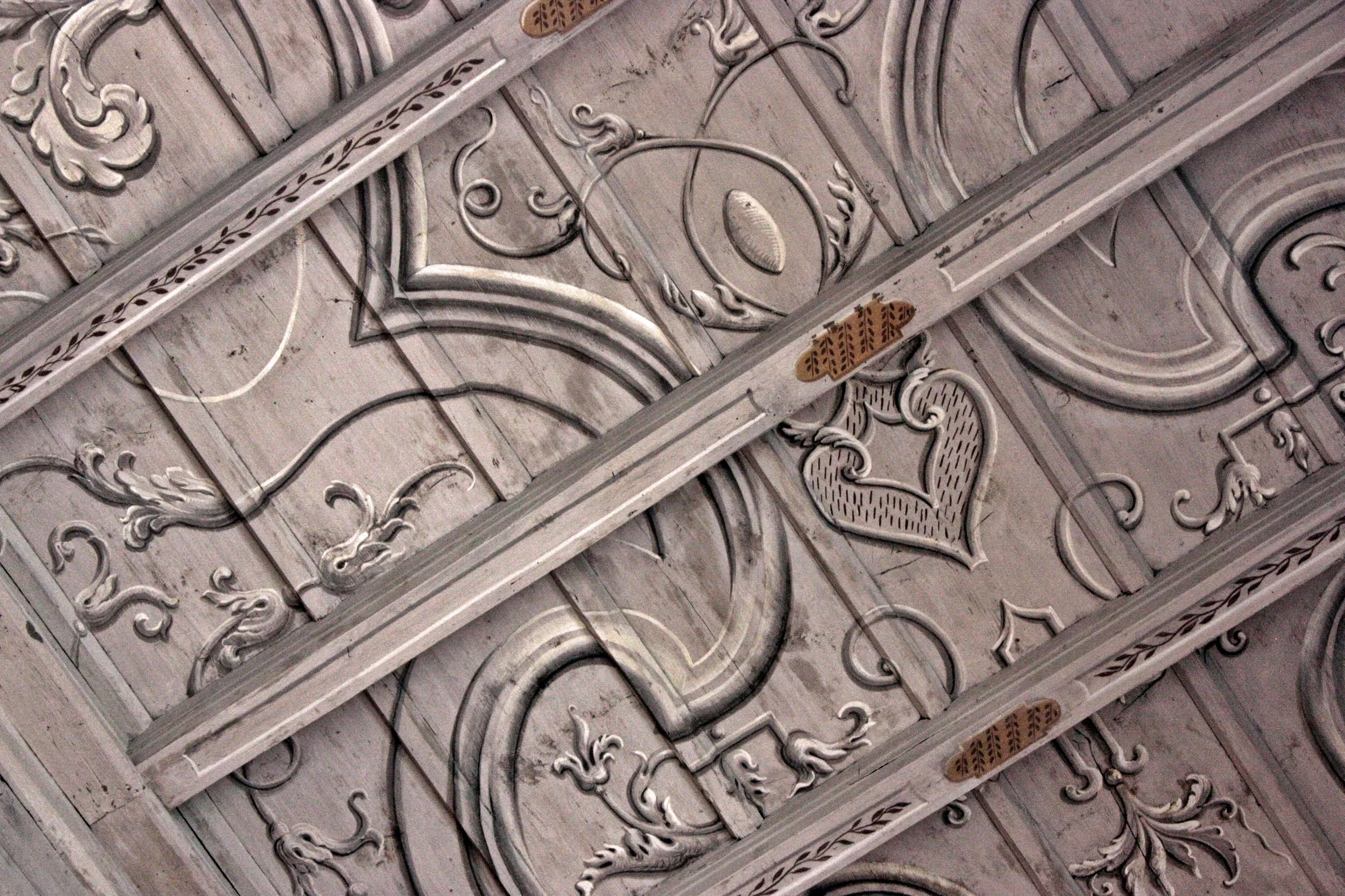 Dettaglio ravvicinato di un soffitto decorato con motivi floreali e ornamentali in stile classico.