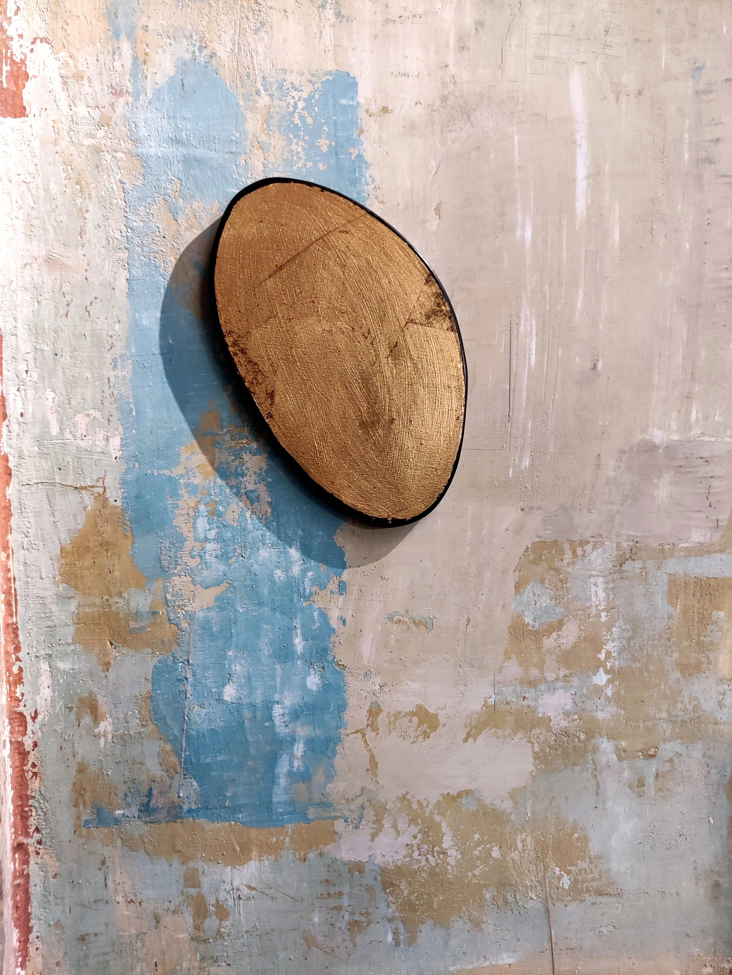 Piatto rotondo in legno davanti a una parete con finitura delabré nei toni del blu, bianco e beige.