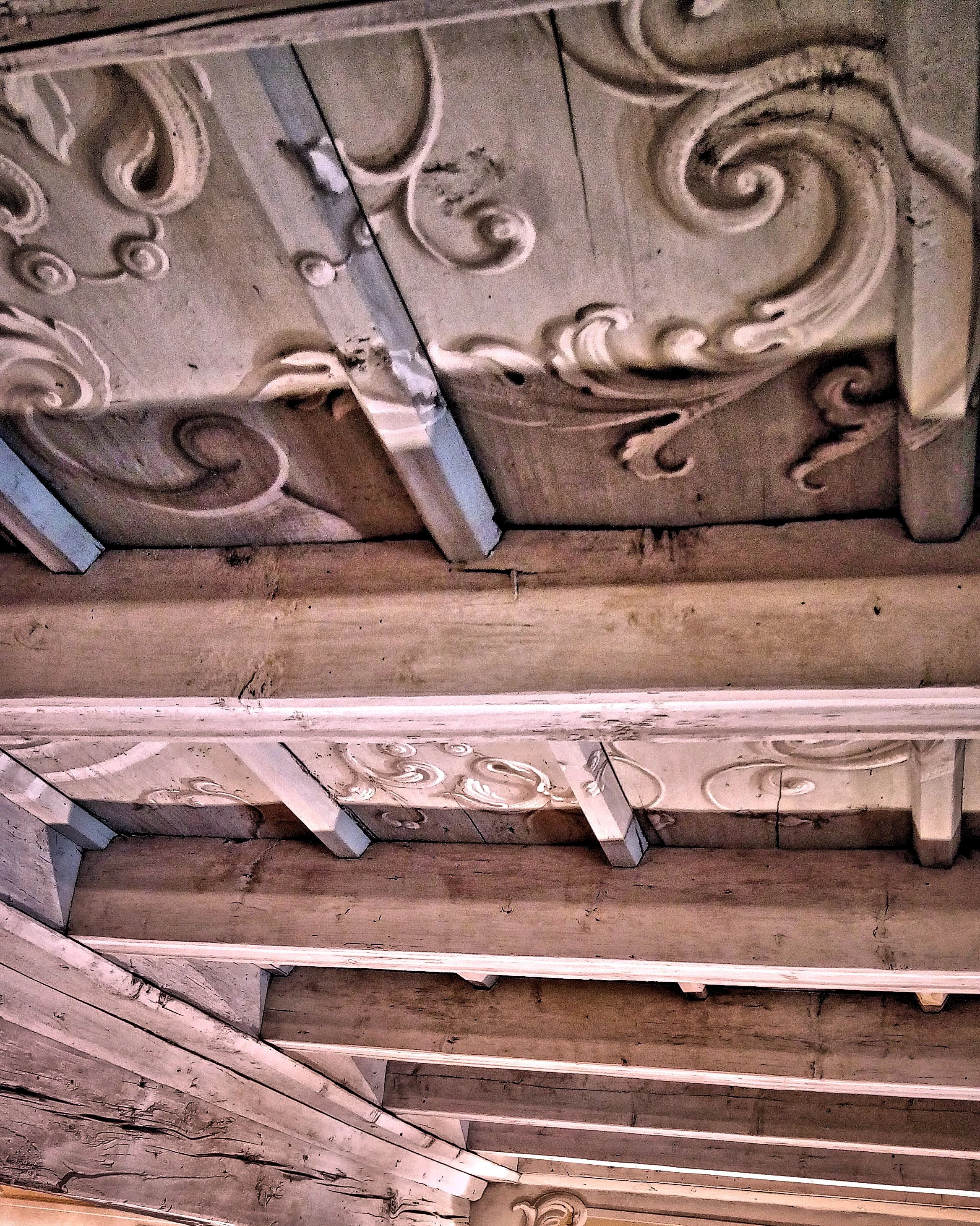 Dettaglio di pannelli in legno decorati con motivi floreali scolpiti e finiture dall'aspetto vissuto.