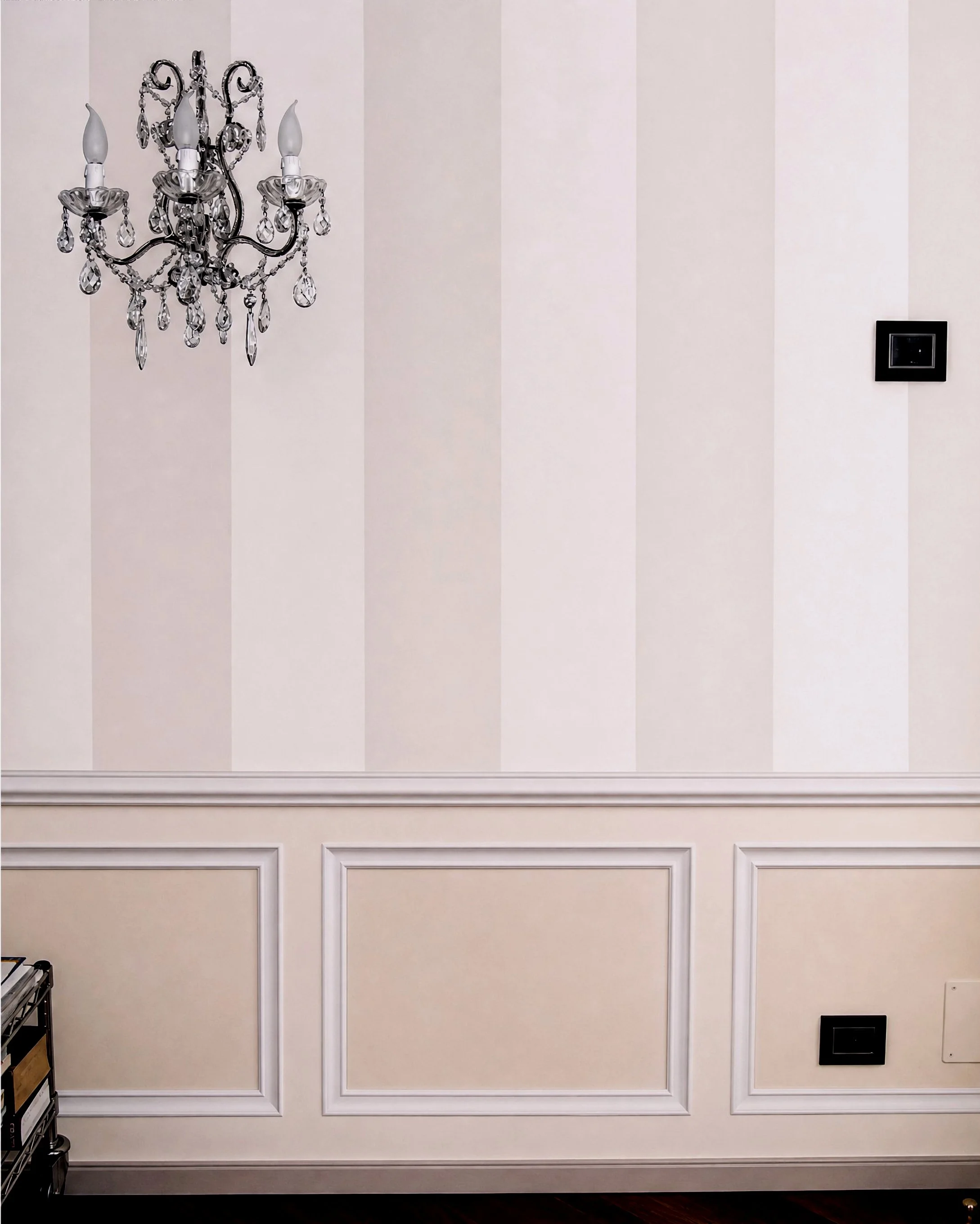Parete con boiserie e modanature decorative nei toni del beige.