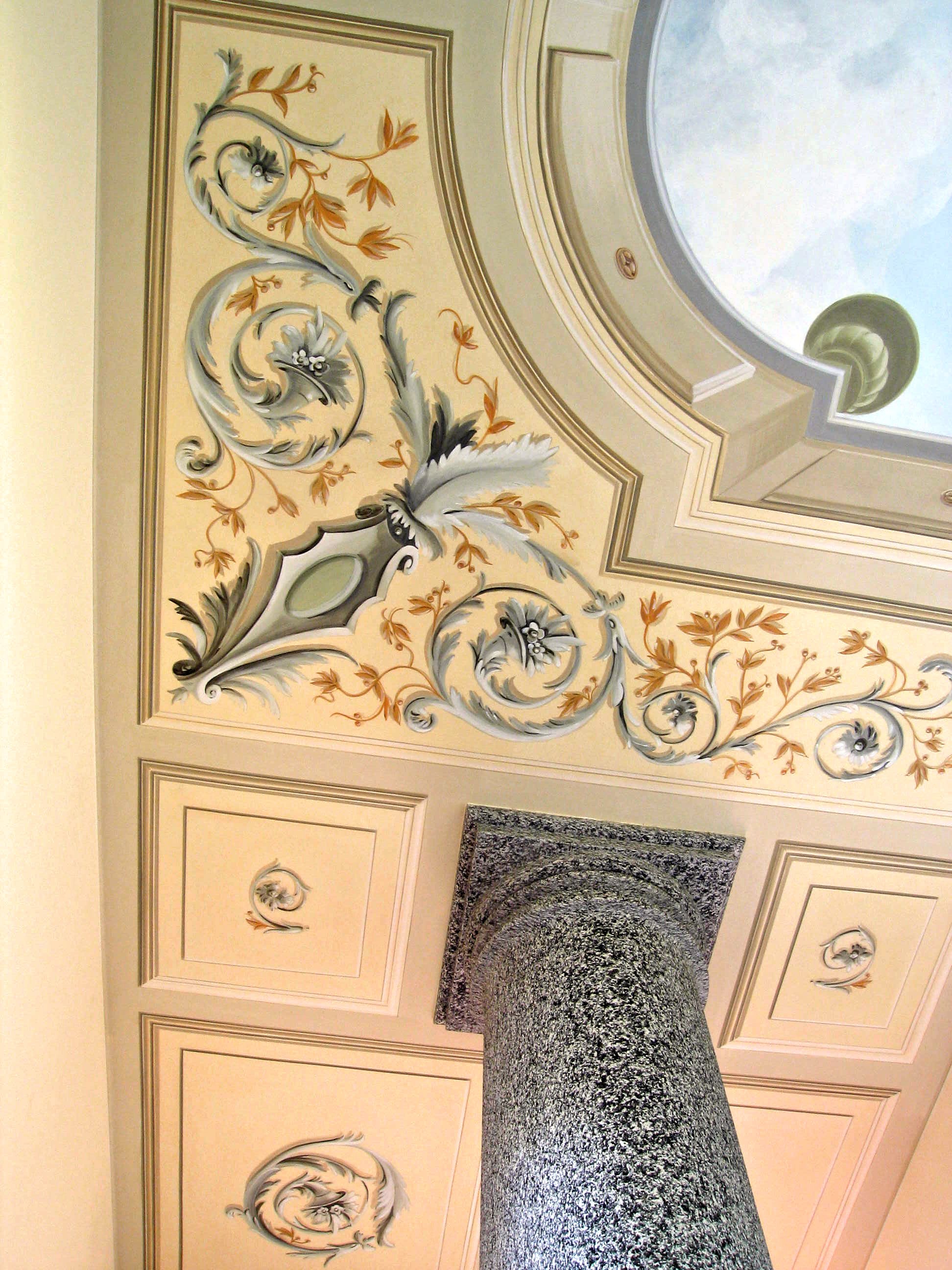 Soffitto decorato con motivi floreali nei toni del beige, grigio e oro, con un elemento architettonico verde al centro.