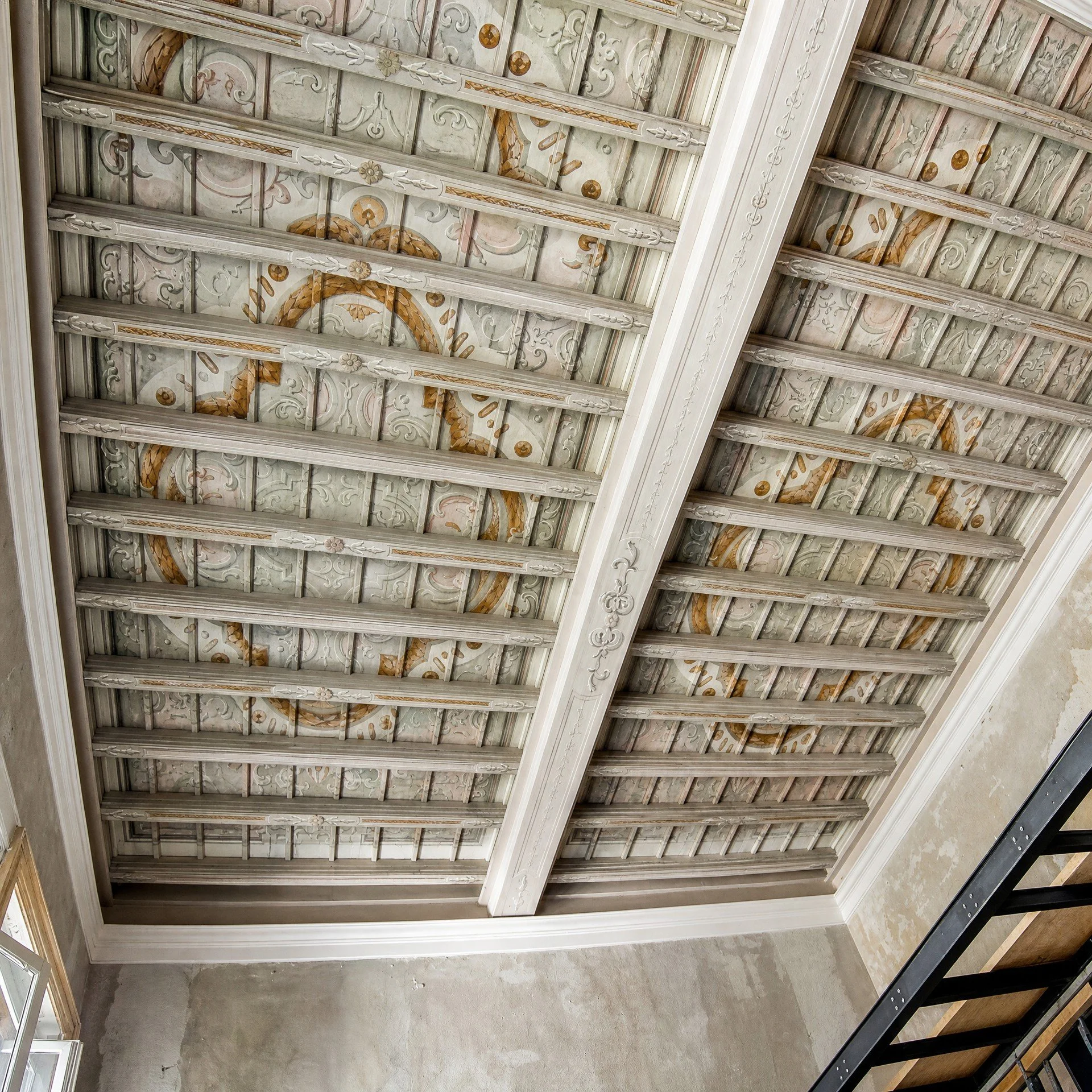 Soffitto con decorazioni pittoriche su legno, caratterizzato da motivi floreali e geometrici.