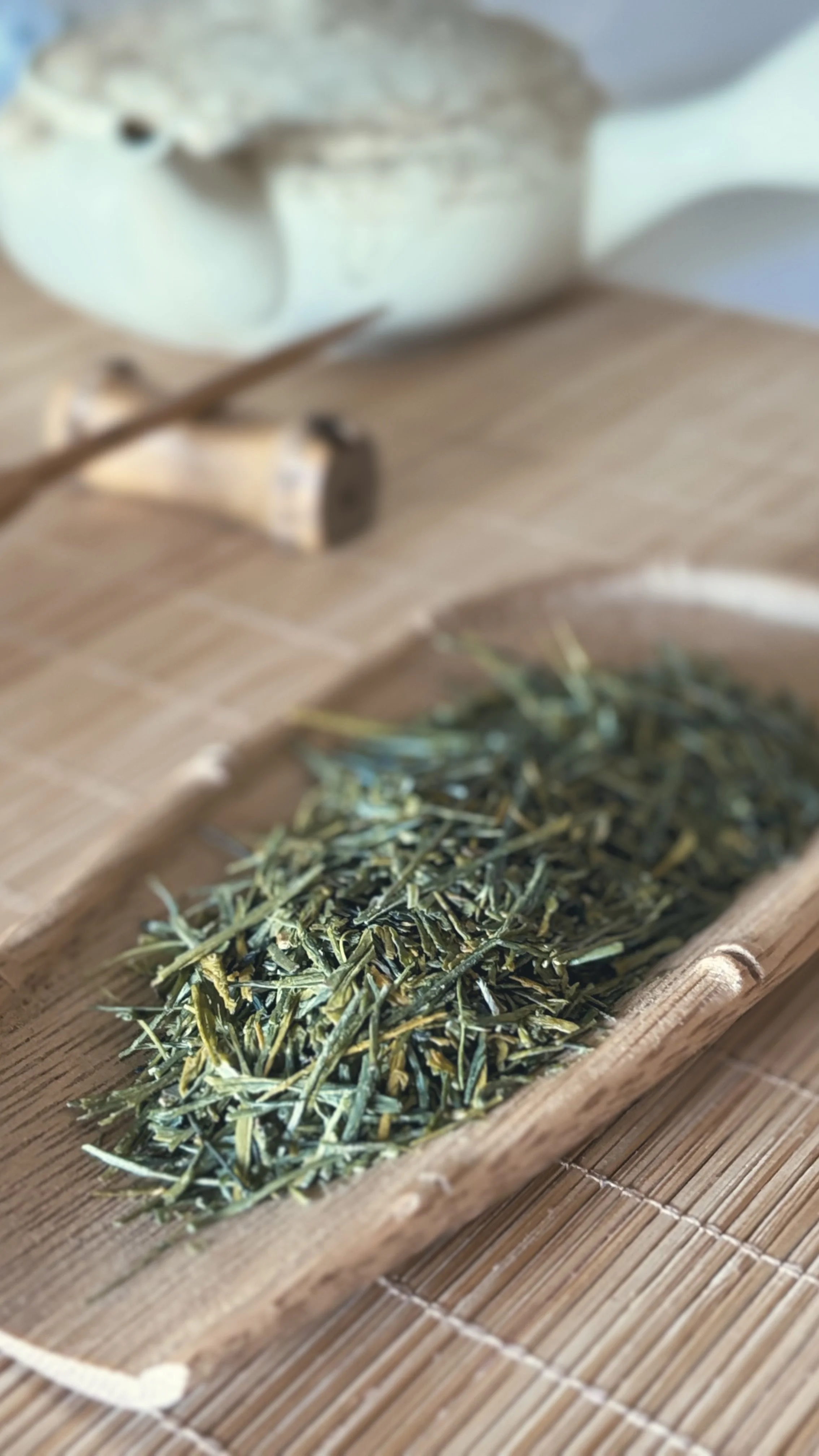 Dried rosemary herb in a wooden tray on a bamboo mat.