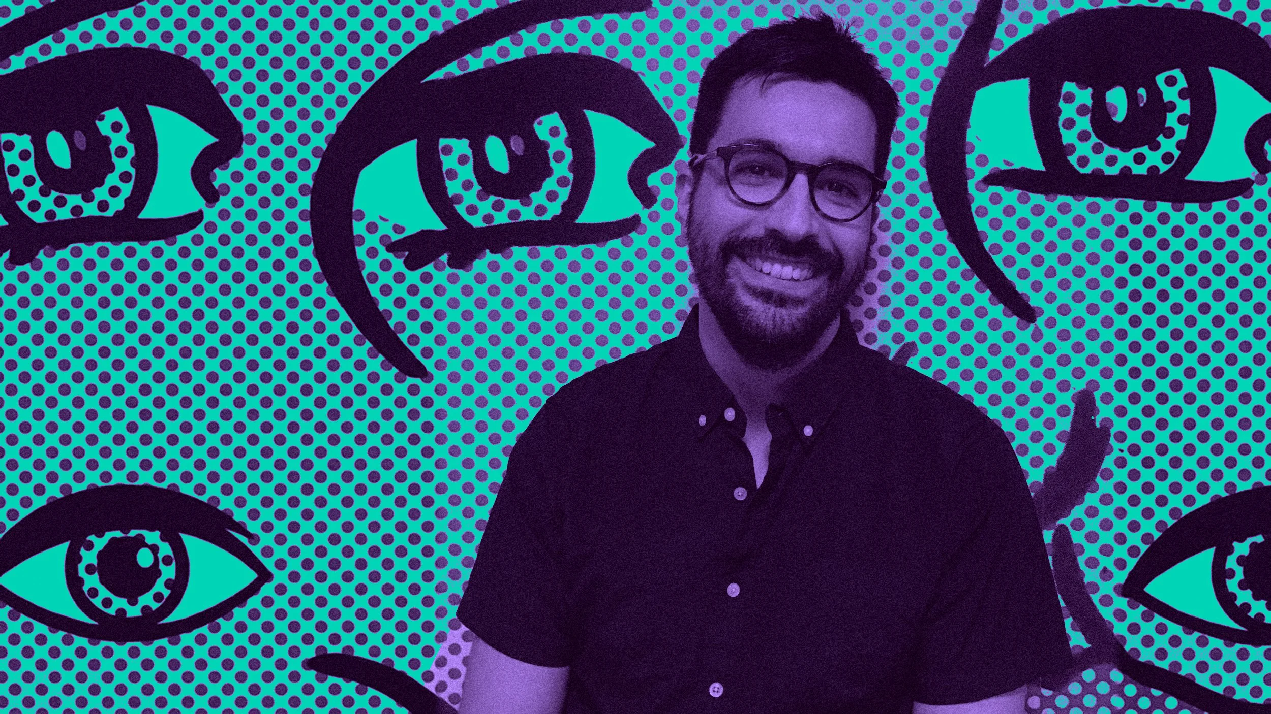 A smiling man with glasses and a beard standing in front of a colorful pop art wall with multiple large eye illustrations.