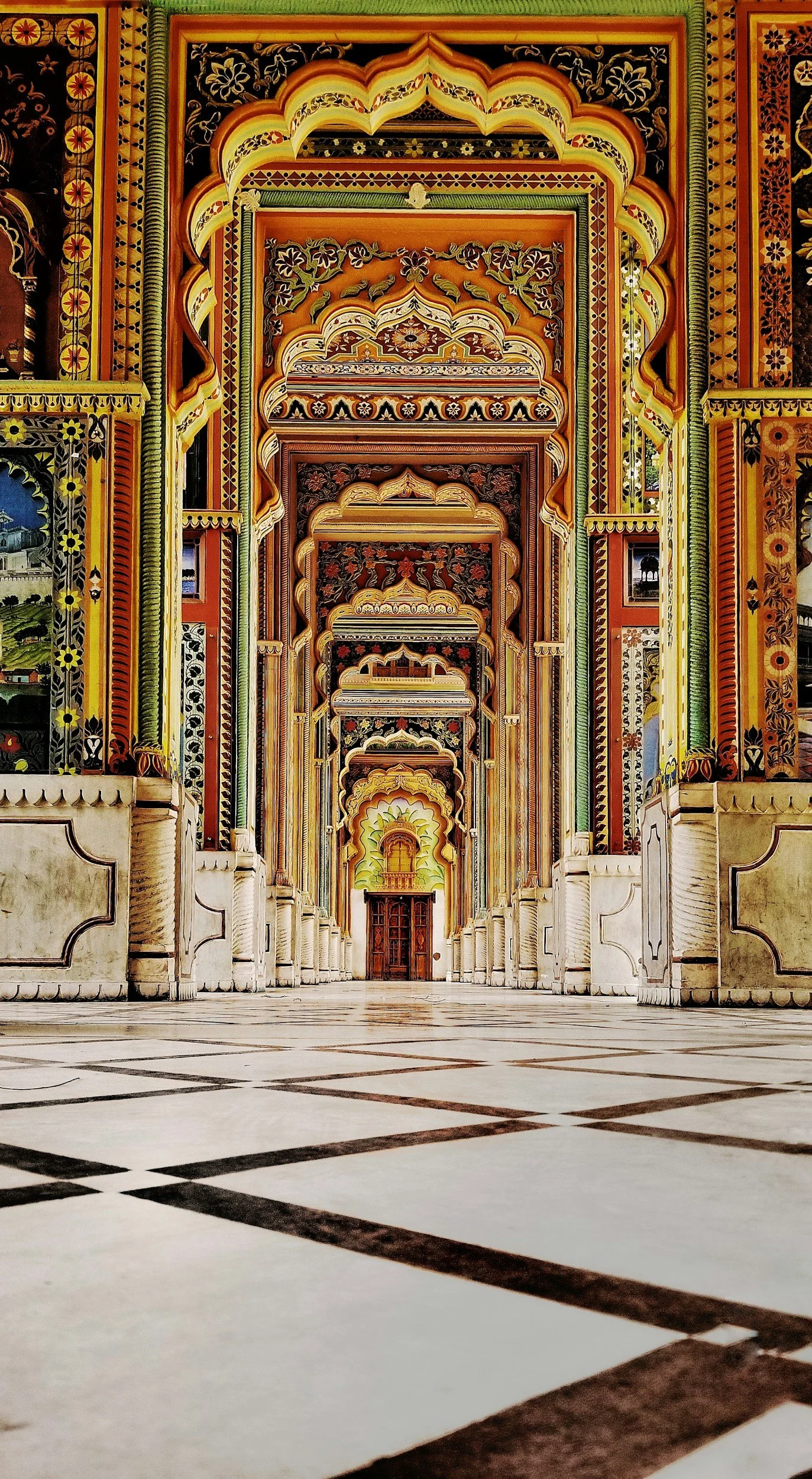 Interior view of a grand, ornately decorated hall with colorful arches and detailed wall designs, leading to a doorway at the far end.