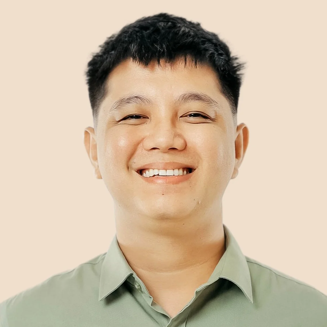A smiling young man with short black hair, wearing a light green collared shirt, against a beige background.