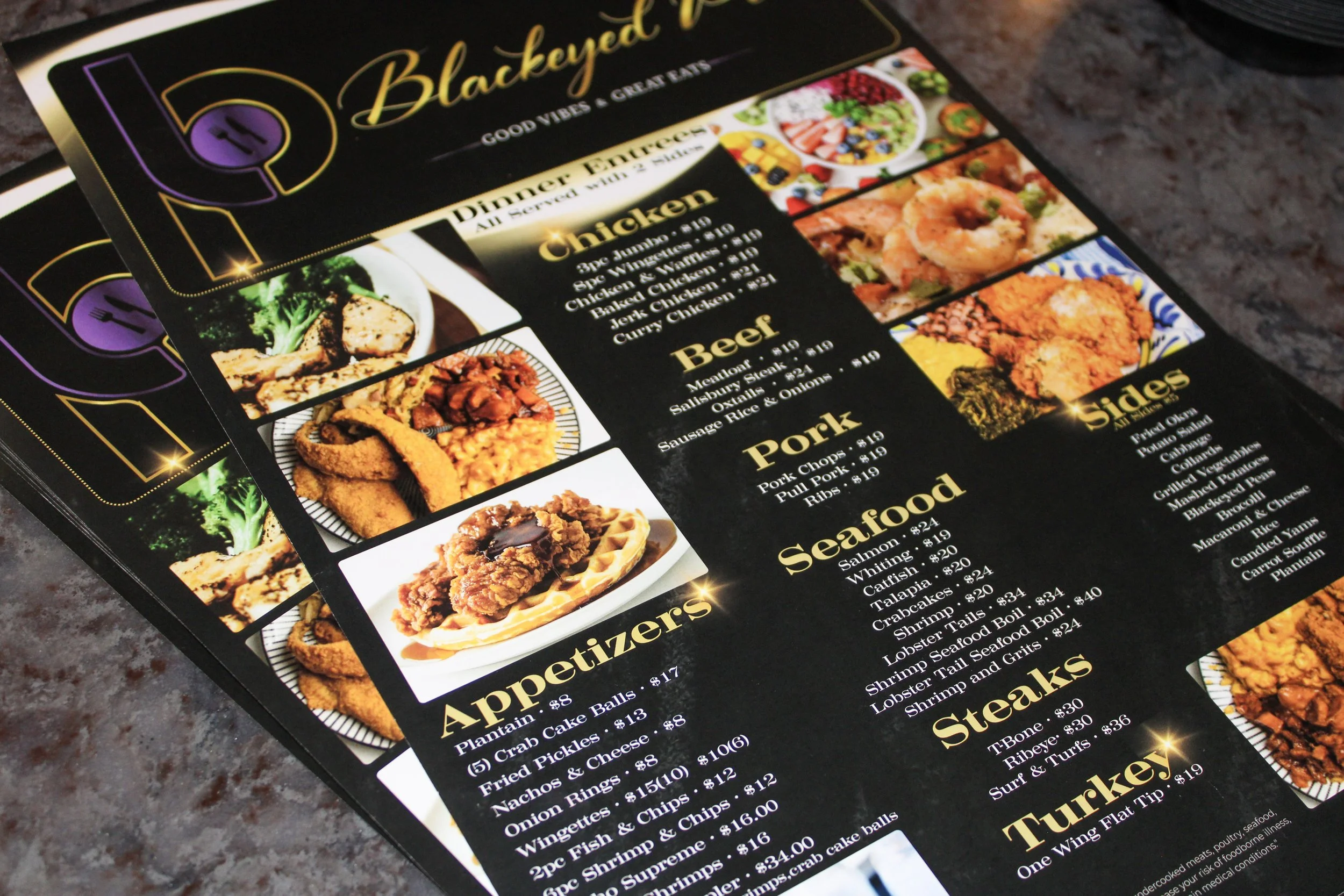 Close-up of a black menu featuring food items such as appetizers, seafood, steaks, turkey, and side dishes with images of various dishes and bright yellow accents.