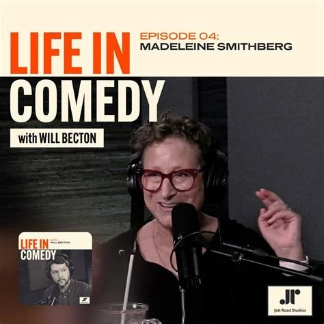 Podcast cover for 'Life in Comedy' featuring Madeleine Smithberg and Will Becton, with a photo of Madeleine Smithberg speaking into a microphone, wearing glasses and headphones.