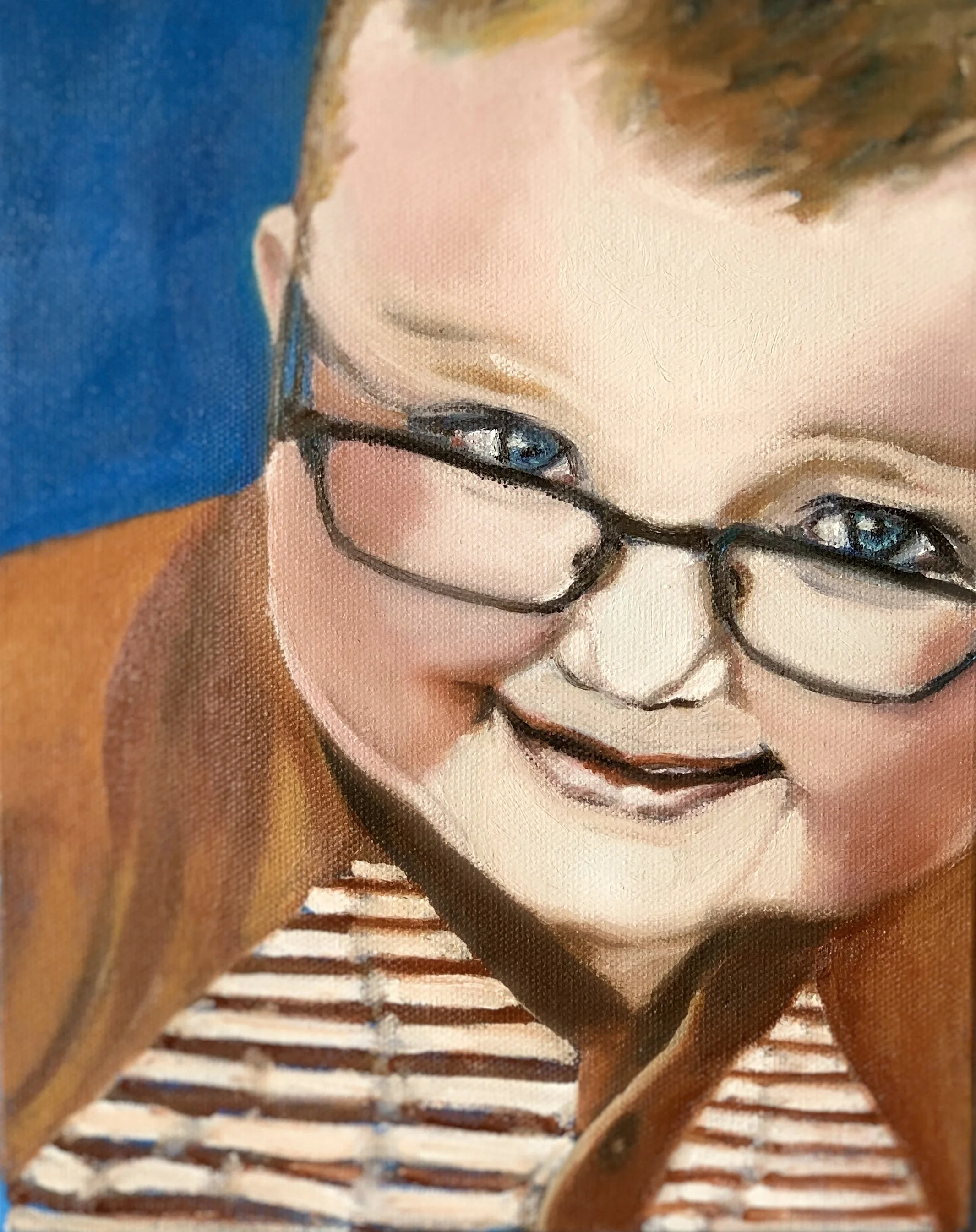 Close-up photograph of a person's face wearing glasses, with brown hair and a striped shirt, focusing on the eyes and facial features.