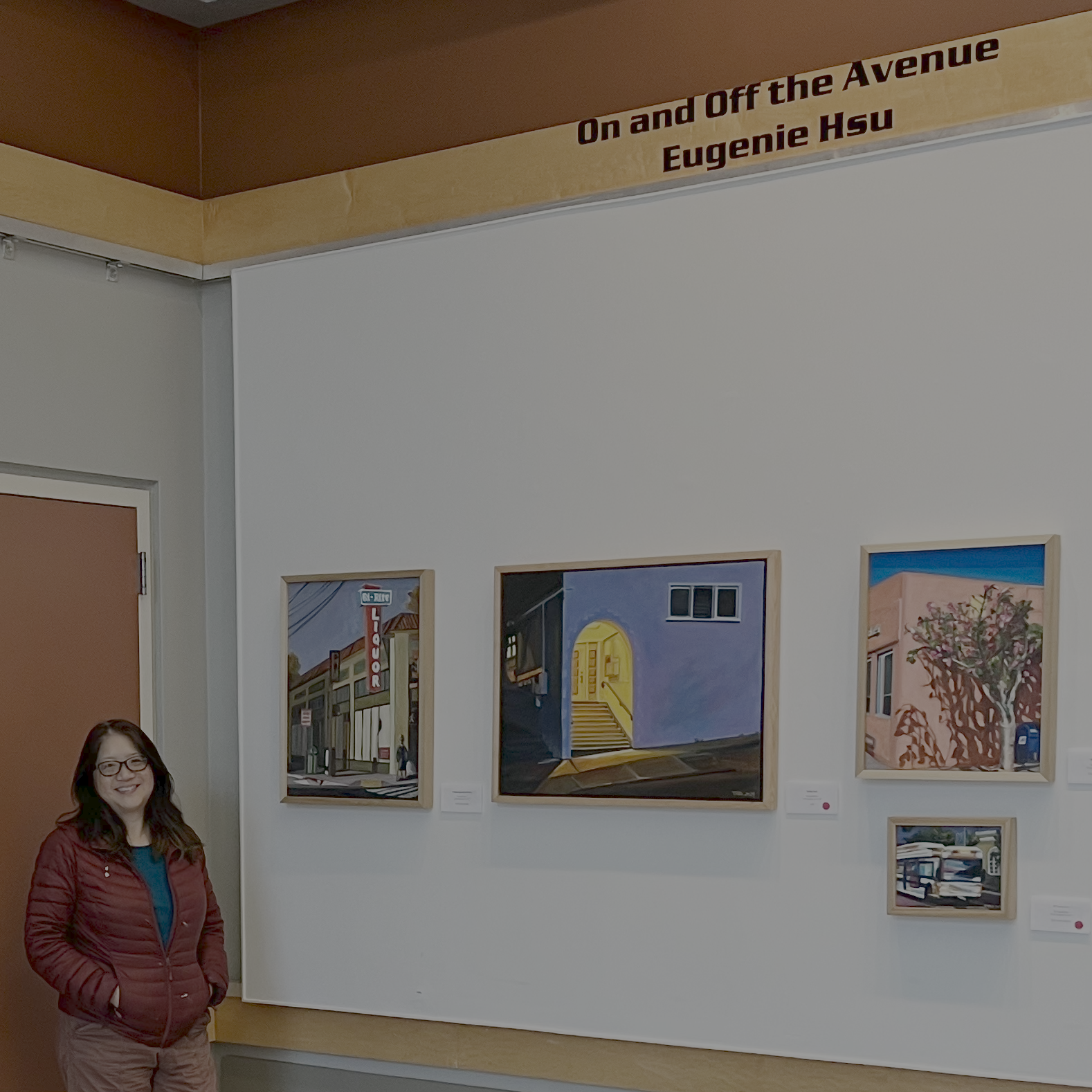 Woman with glasses and red jacket standing in front of artwork on gallery wall, titled 'On and Off the Avenue' by Eugene Hsu.