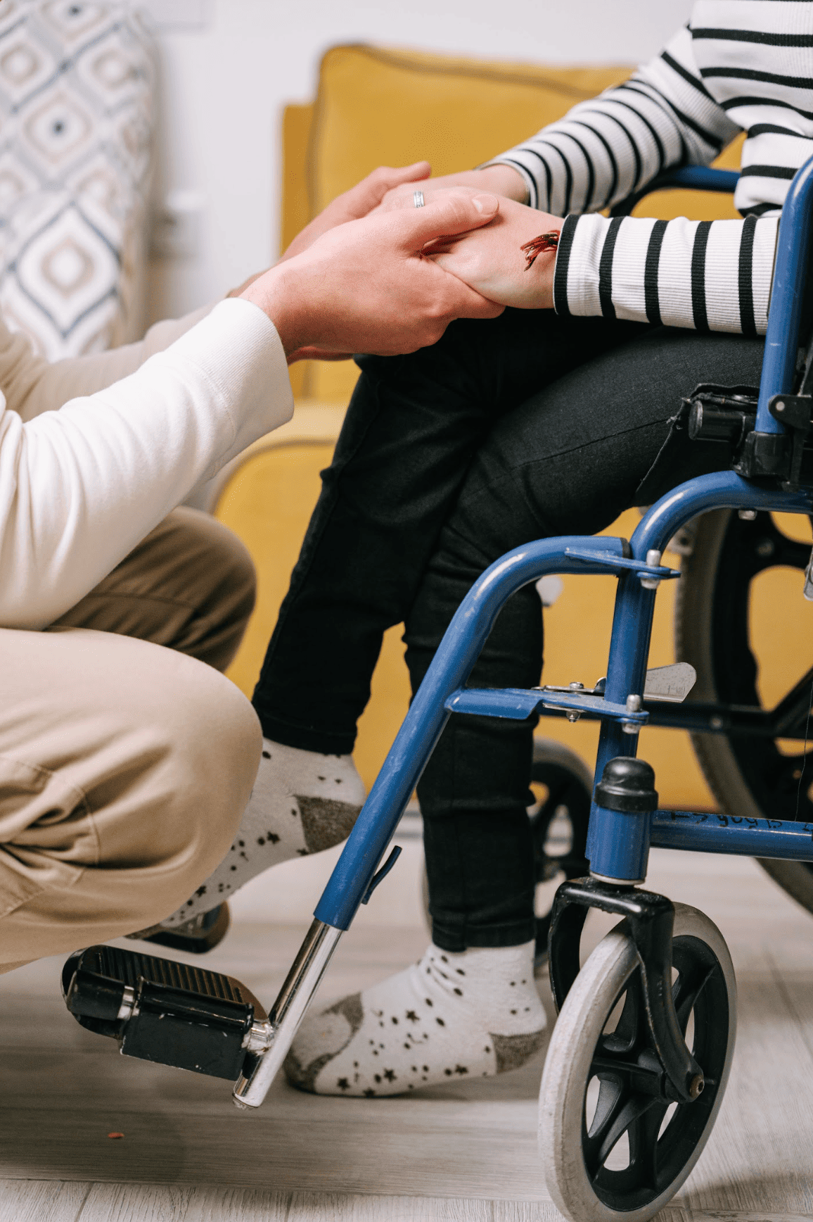 Une personne en fauteuil roulant tenant la main d'une autre personne, lors d'une rencontre ou d'une séance de soutien