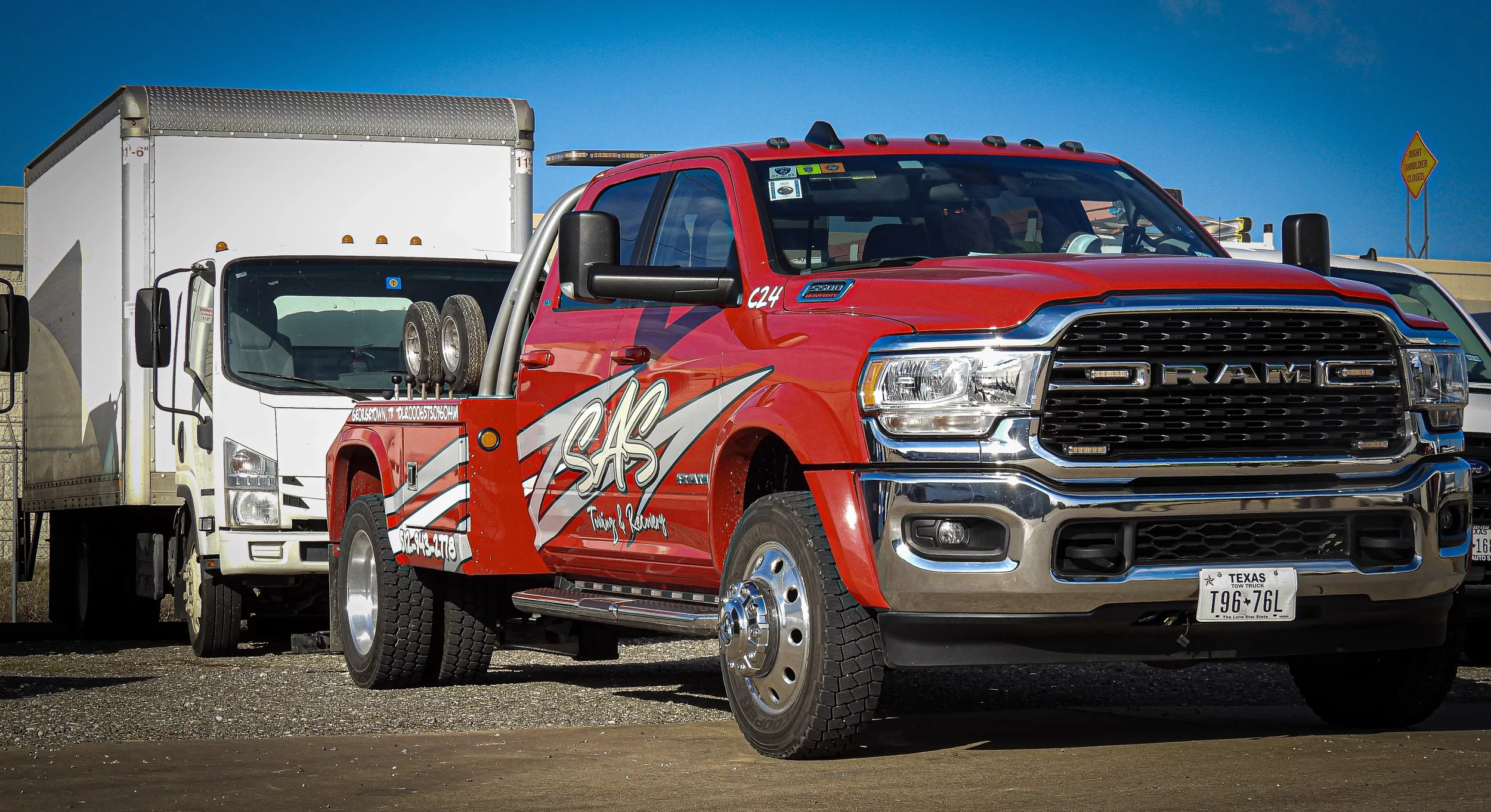 Red SAS Road Solutions pickup truck beside a white box truck