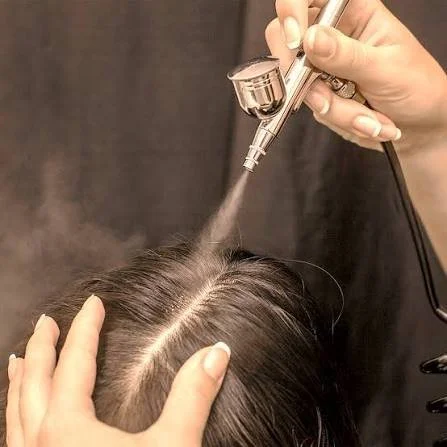 Person getting a scalp micropigmentation procedure with a tattoo pen on the scalp.