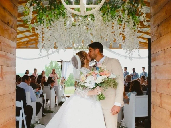 A bride and groom sharing a kiss under floral decorations at their wedding reception.