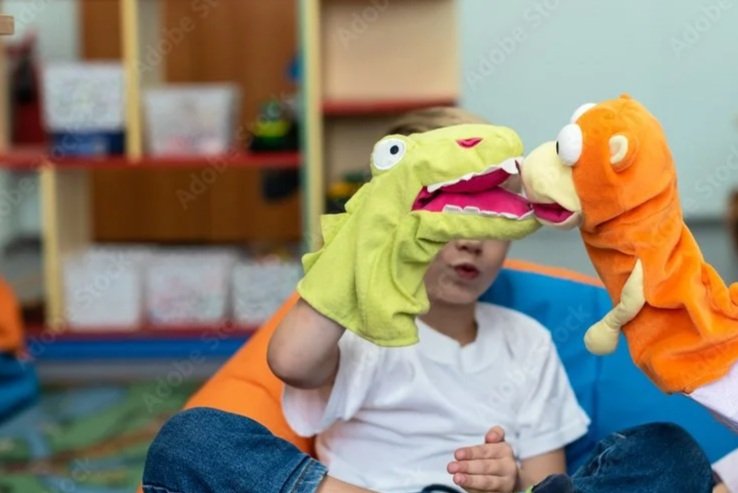 Child wearing dinosaur gloves as puppet monsters during a play session