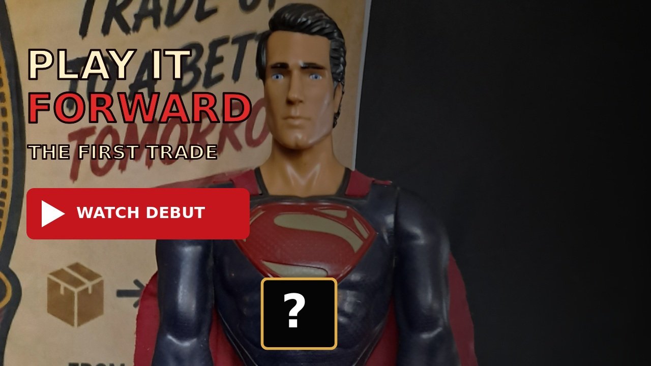 A toy figure of Superman wearing a black suit with a red and gold emblem on the chest, and a red cape, standing in front of a background with text and graphics.
