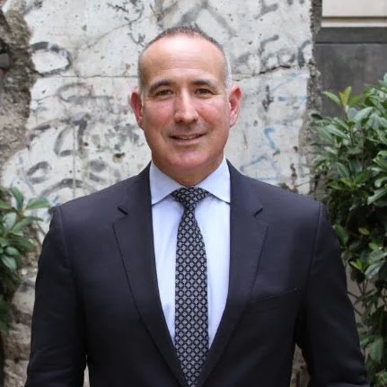Portrait of Dr. Albert “Jim” Marckwardt wearing a dark suit and tie outdoors.