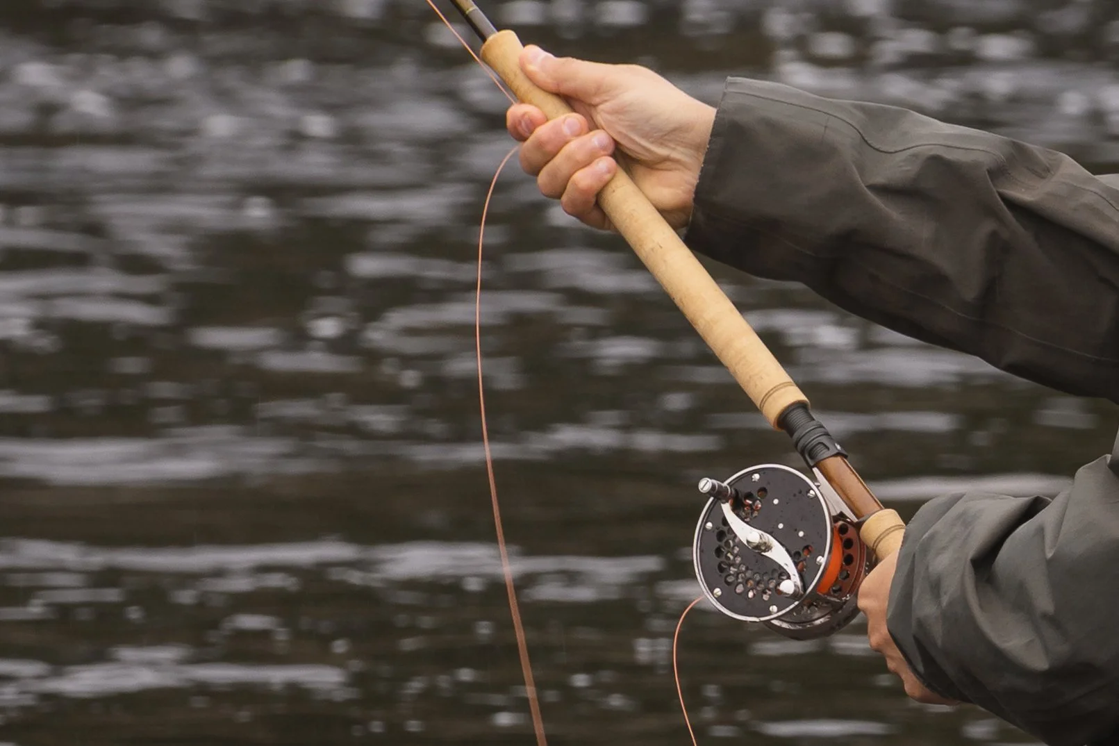 Hand lifting a Sage R8 fly rod and Loop classic reel mid-cast above the river