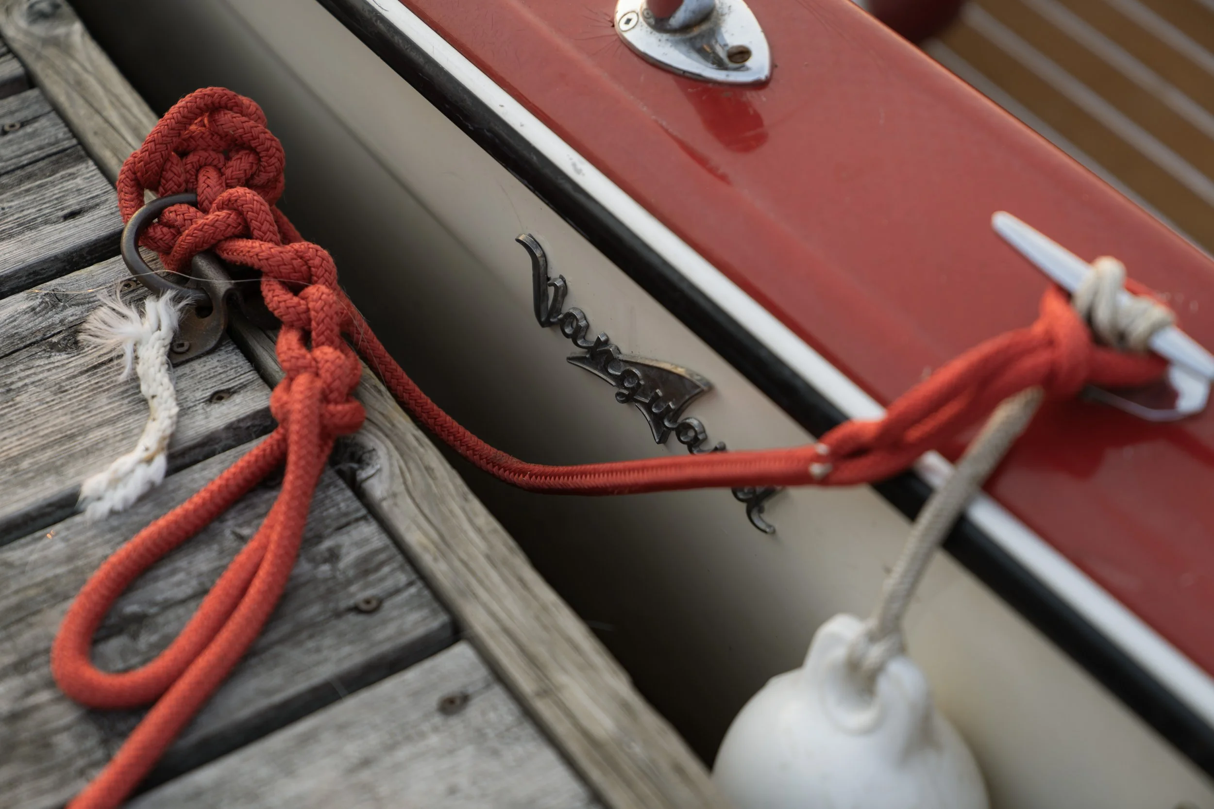 Coiled red dock line beside the chrome Vanguard badge on a boat hull