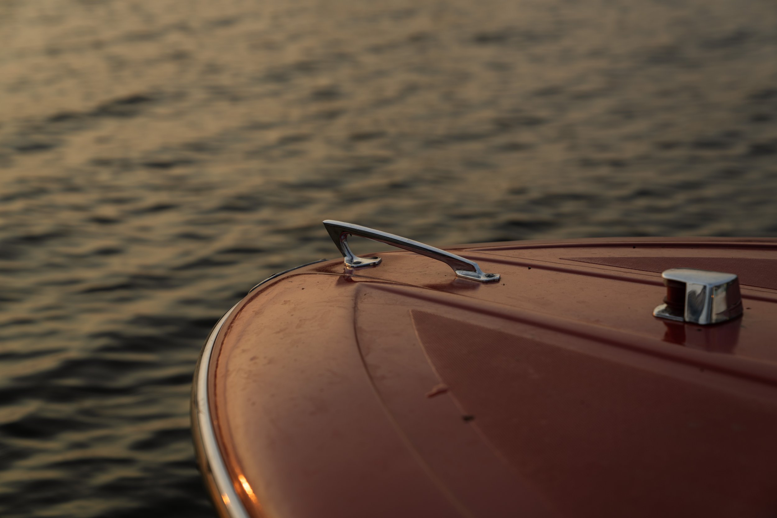 Bow of a runabout over golden water at sunset