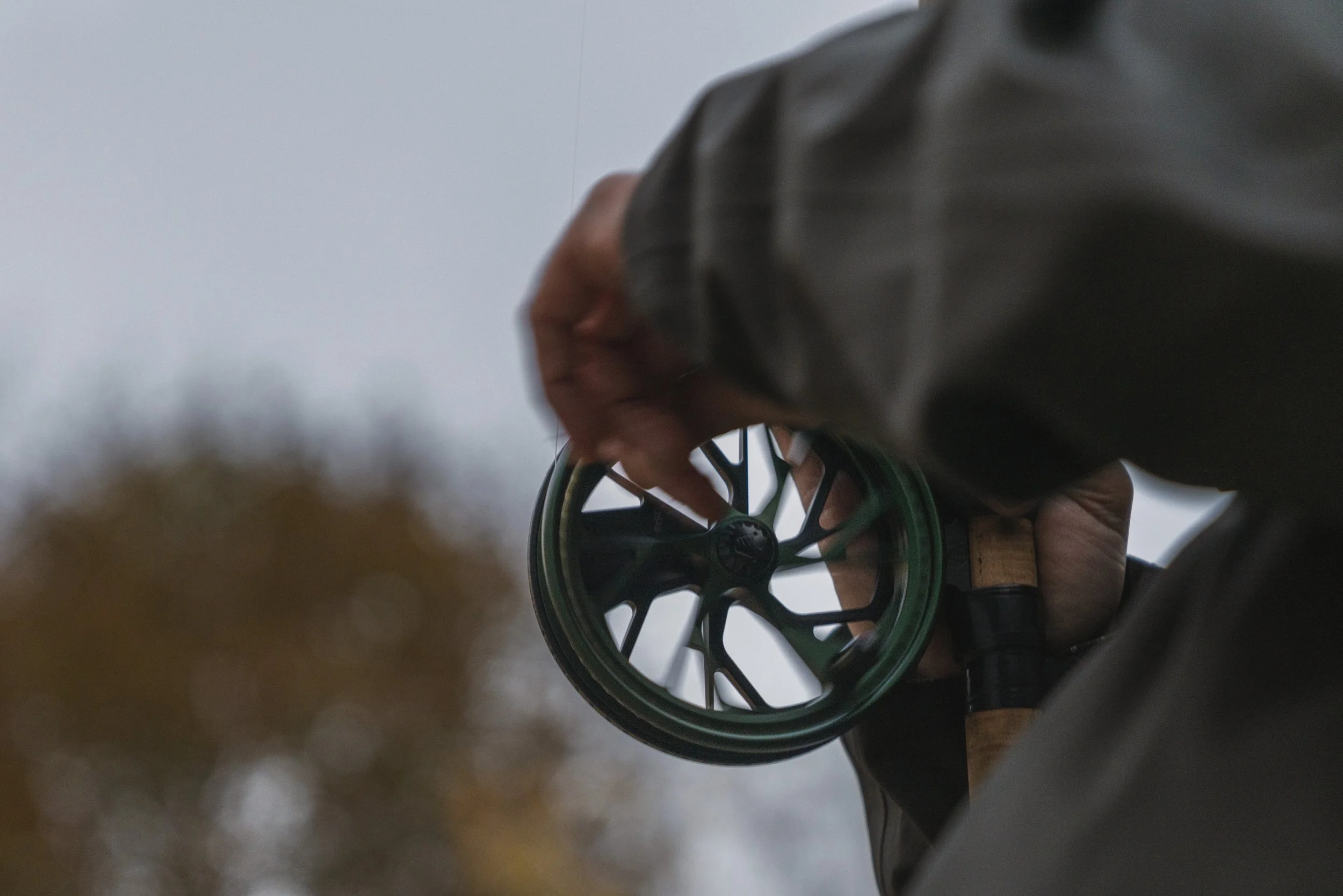 Close-up of a Kingpin Zodiac reel held in hand against a backdrop of autumn colour