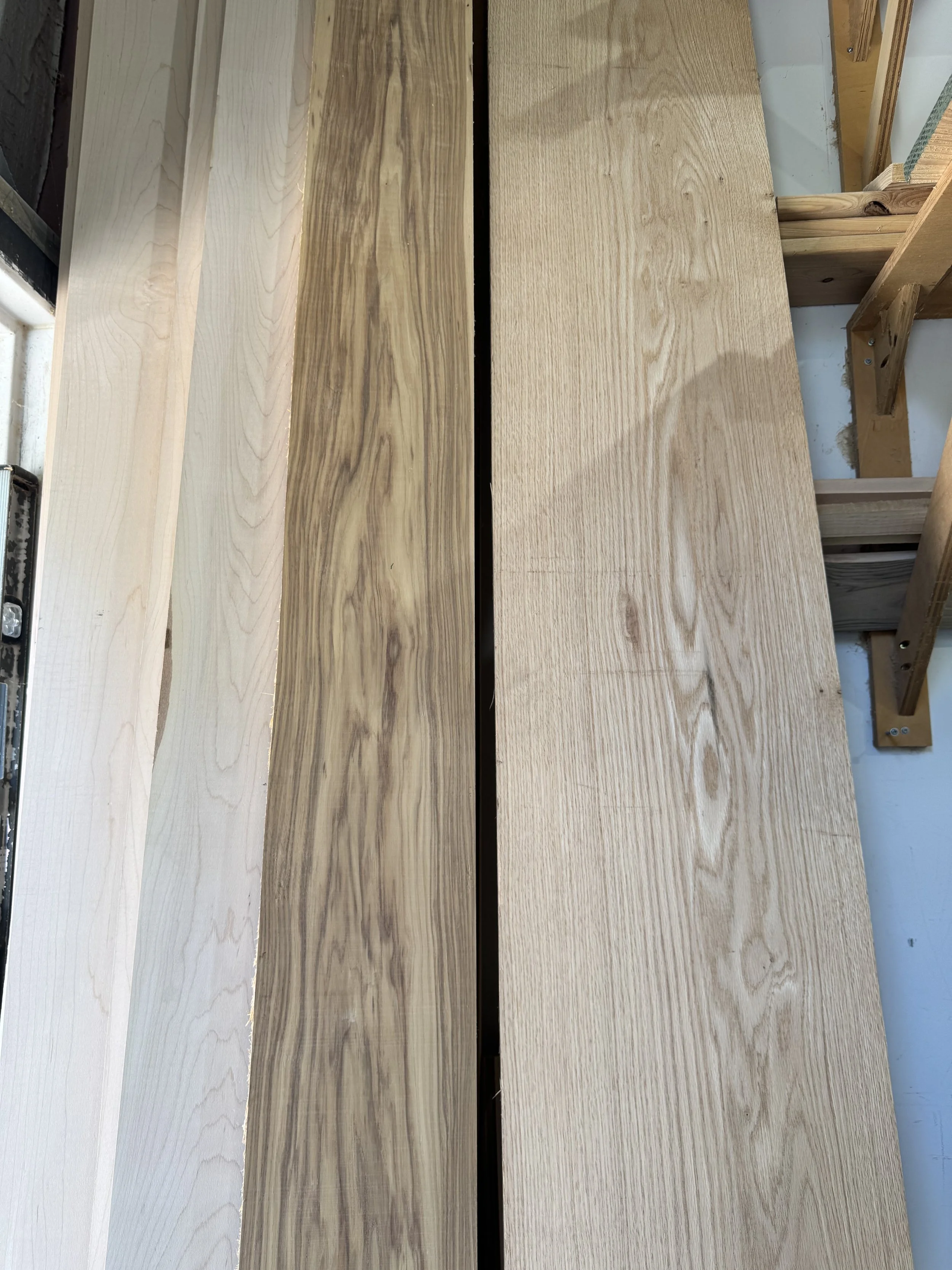 Various pieces of natural unfinished wood in different shades and grain patterns stacked or laid side by side.