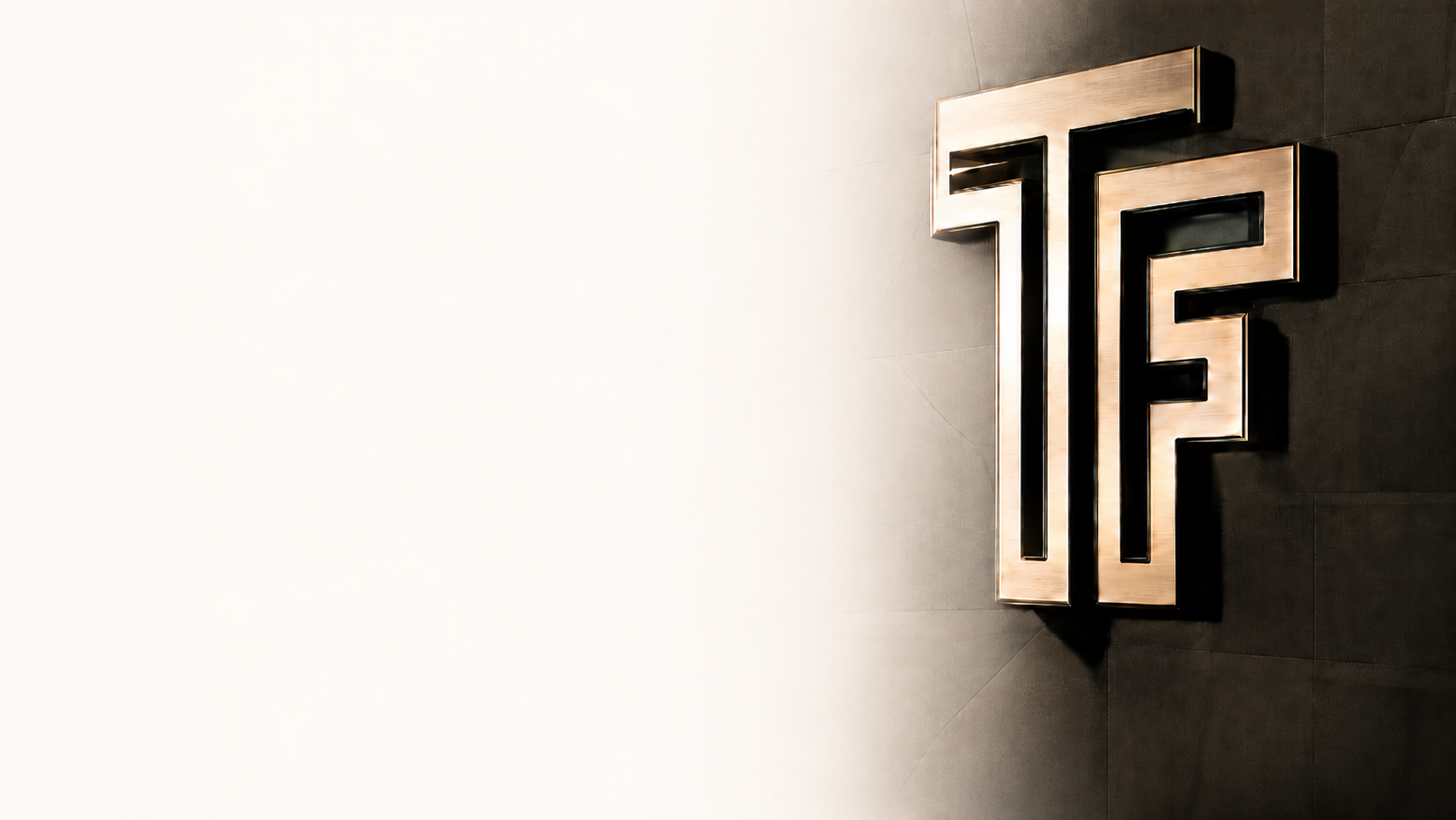 Close-up of a large illuminated logo with the initials 'TF' mounted on a dark wall, with a blank white wall to the left.