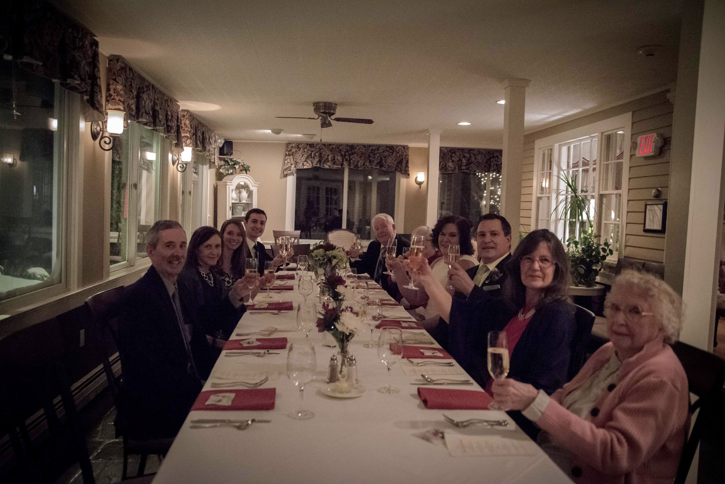 Guests raising champagne glasses at the long dinner table.