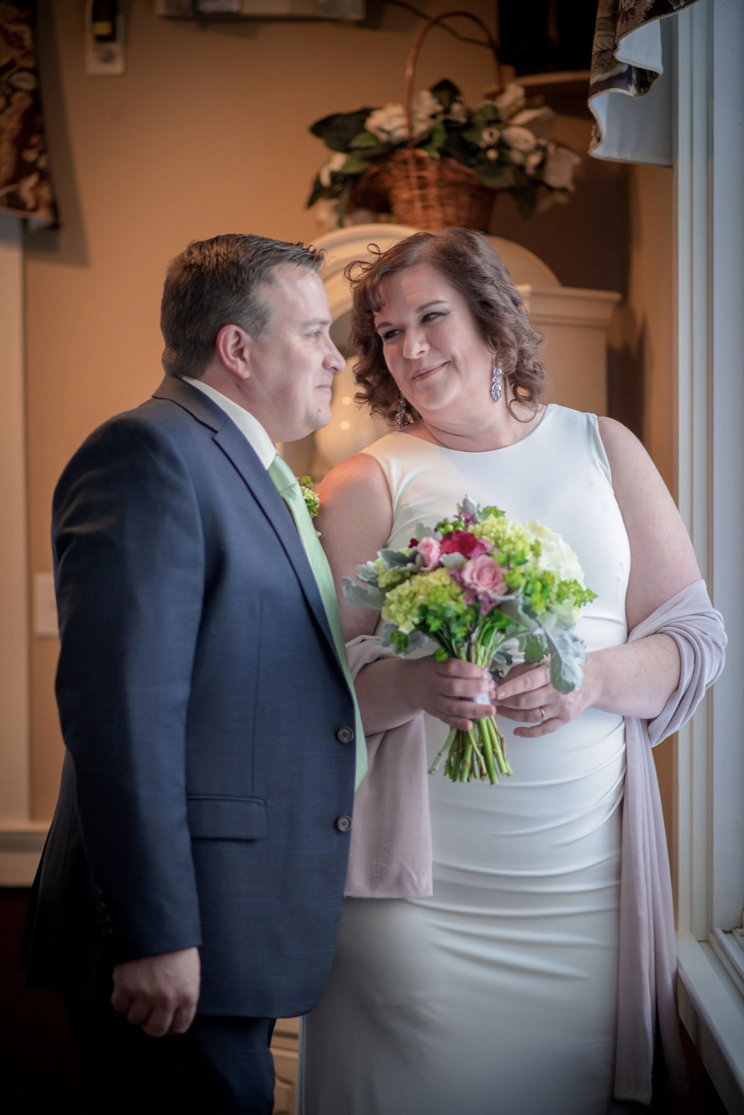 A formal bride-and-groom portrait by an indoor window.