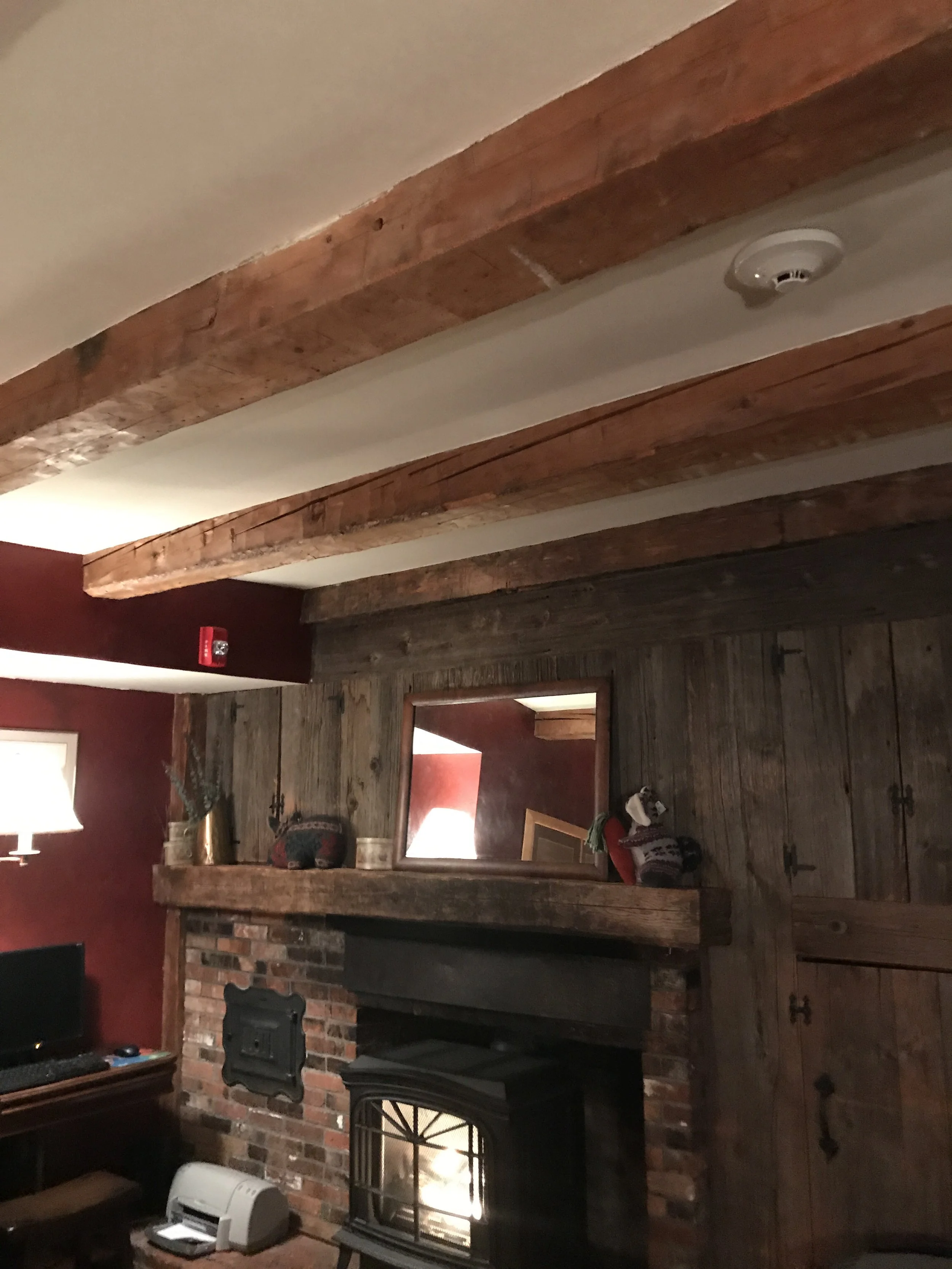 A rustic inn interior with wood beams and a brick fireplace.