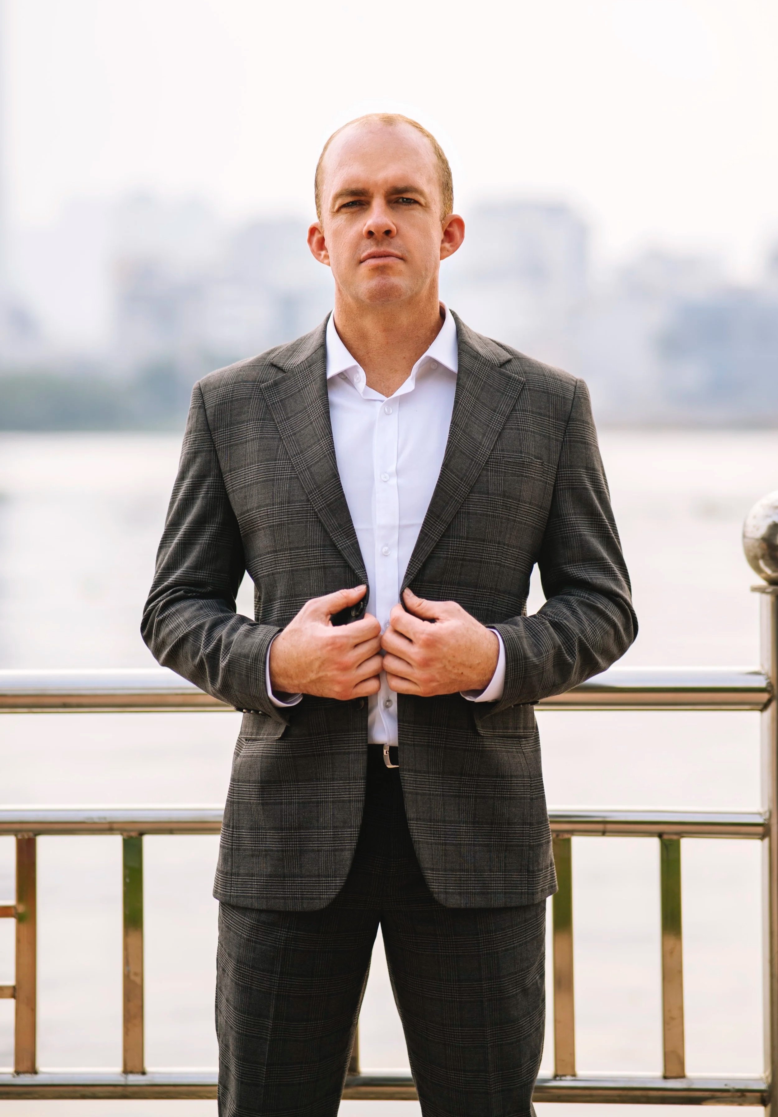 Professional portrait of Aaron Hannemann standing outdoors overlooking the waterfront in Vietnam.
