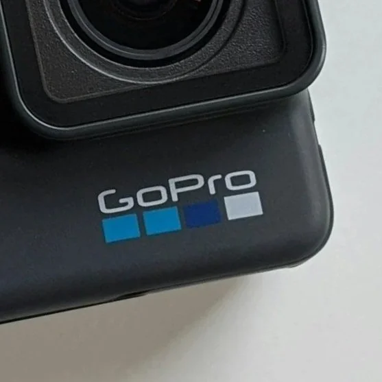 Close-up of a GoPro camera with a logo featuring four colored squares, placed on a flat surface.