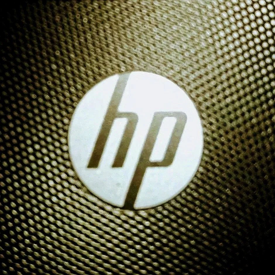 Close-up of a white circular HP logo on a textured, brown fabric surface.