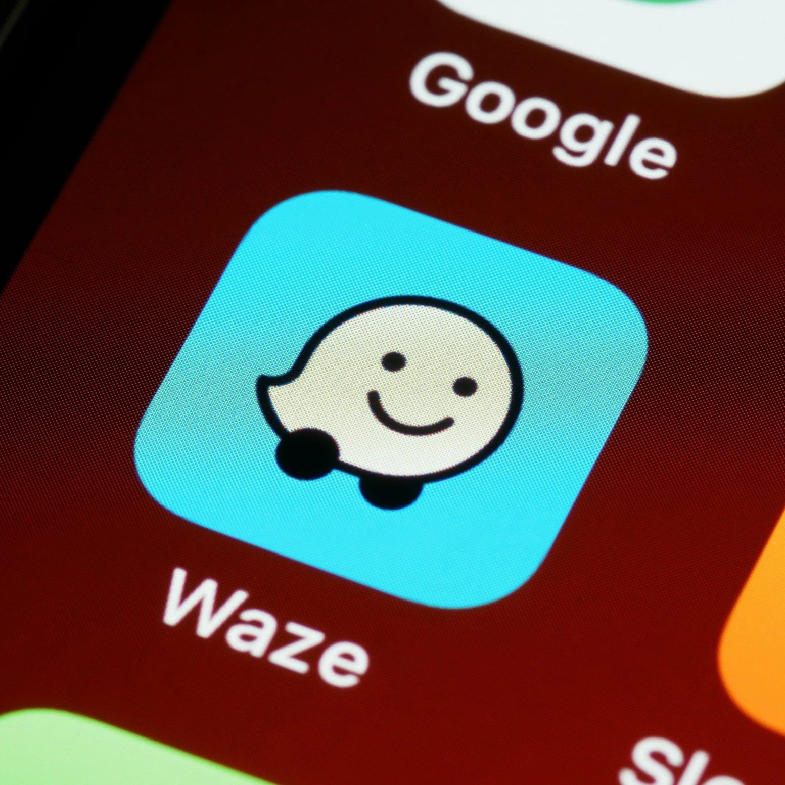 Close-up of a smartphone screen displaying the WiZ app icon, which features a smiling cartoon face with a headset, on a red background.