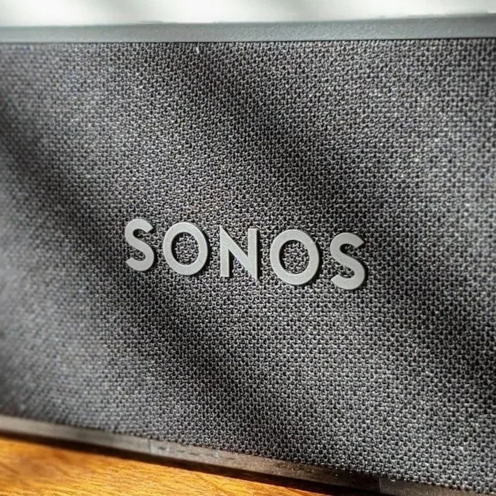 Close-up of a textured black speaker with the brand name "Sonos" in silver letters.