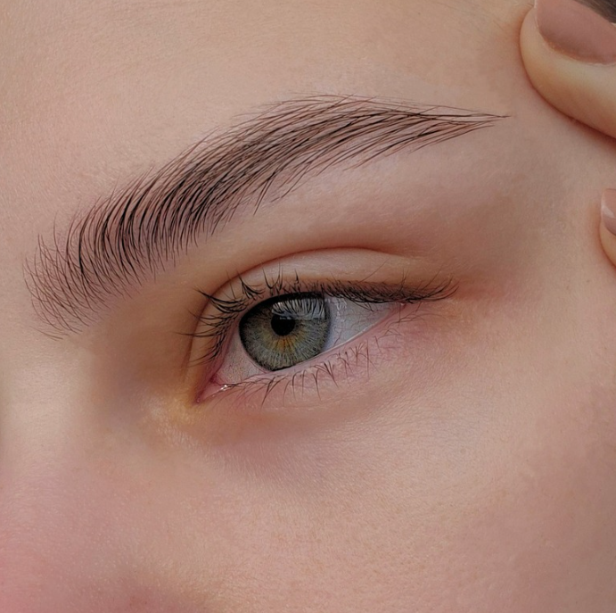 Close-up of a human eye with light-colored iris and well-groomed eyebrow. Brow shaping results by k.beautystudio aberdeen.
