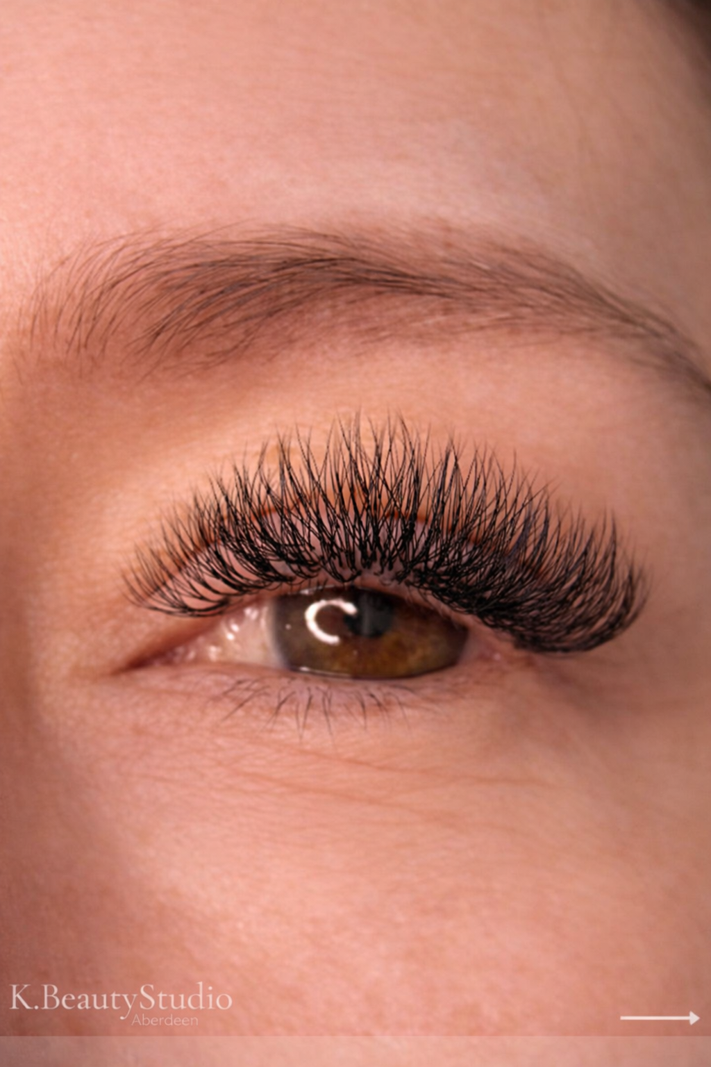 Close-up of a person's eye showing full volume Russian lash extensions, deep brown eyes with a lightly shaped brown eyebrow at k.beautystudio Aberdeen.