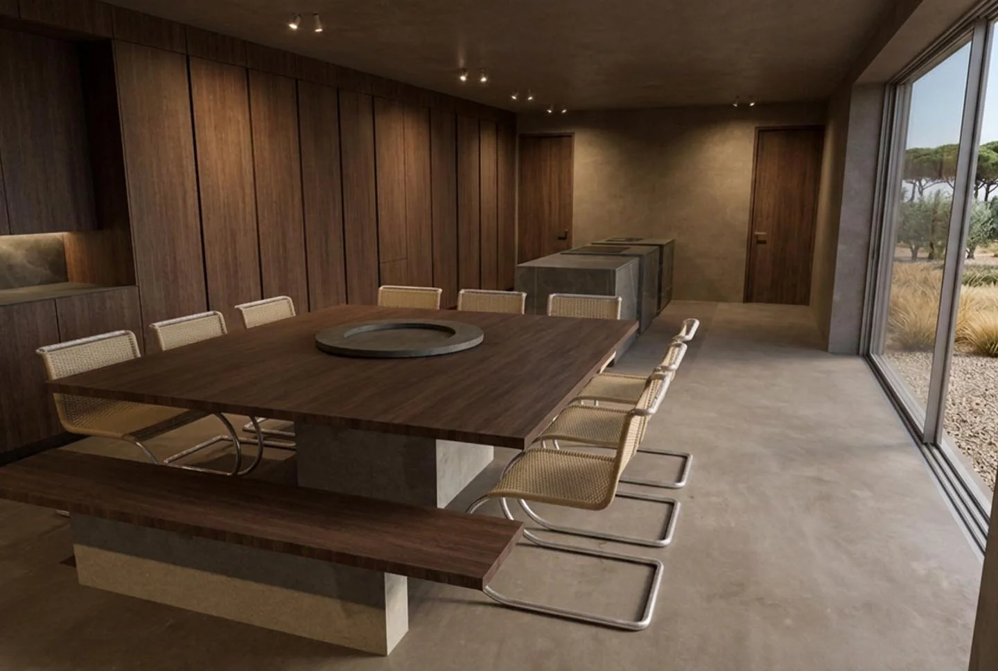 Modern dining room with a large wooden table and nine light-colored chairs, wood-paneled walls, concrete flooring, large windows showing outdoor trees, and built-in cabinets.