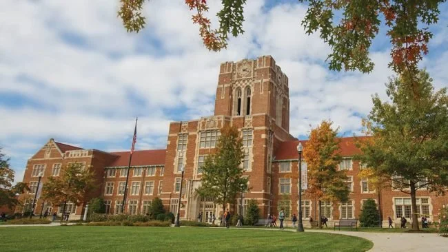 University of Tennessee Southern, a historic brick school building with a clock tower, surrounded by trees with autumn-colored leaves and a grassy area in front.