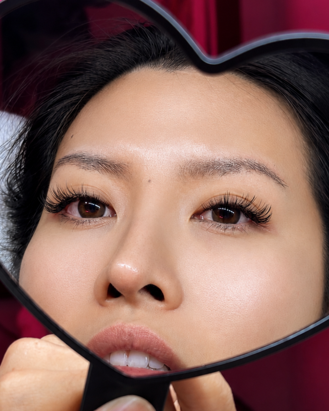 A woman with makeup looking into a mirror, with her face reflected in it.